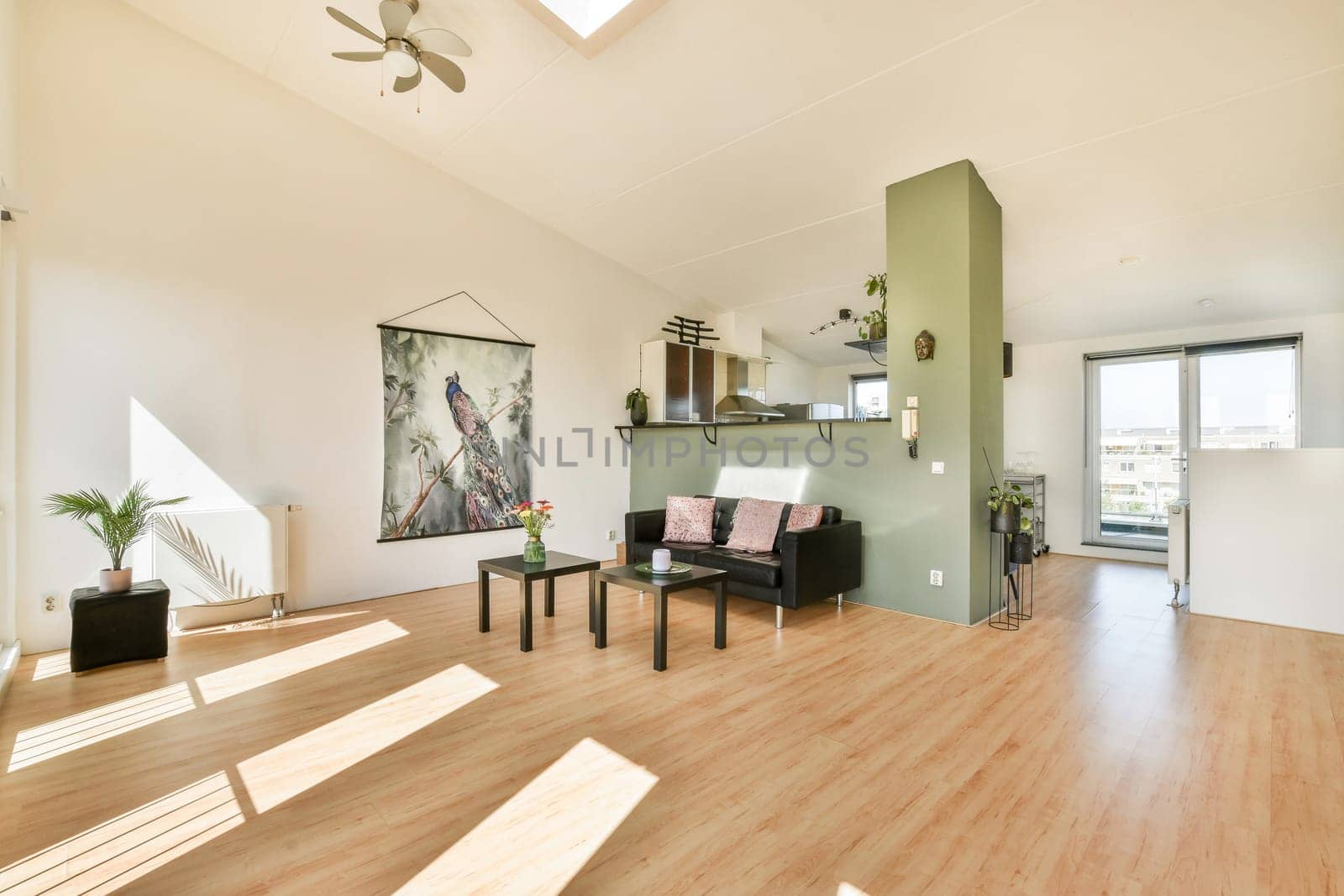 A spacious modern interior showcasing natural light, minimalistic furniture, and elegant decor. The room features neutral colors and a touch of greenery for a cozy ambiance.