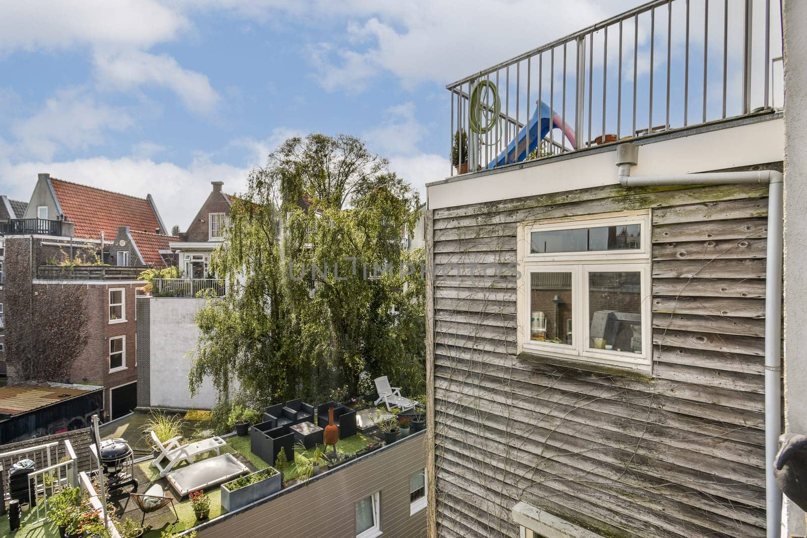 A vibrant rooftop scene showcasing lush trees, modern architecture, and a clear blue sky, perfect for urban relaxation and nature appreciation.