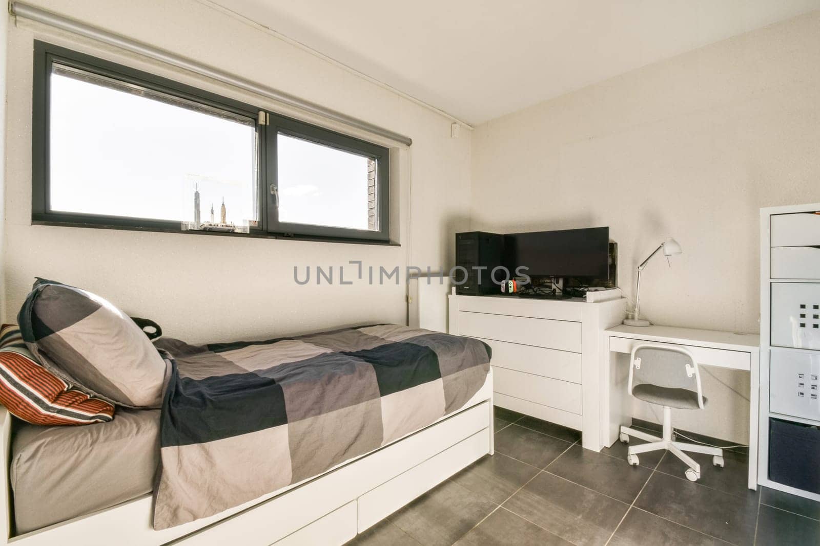A stylish modern bedroom featuring a bed with patterned bedding, a dresser, and a desk, all within a bright, minimalist aesthetic.
