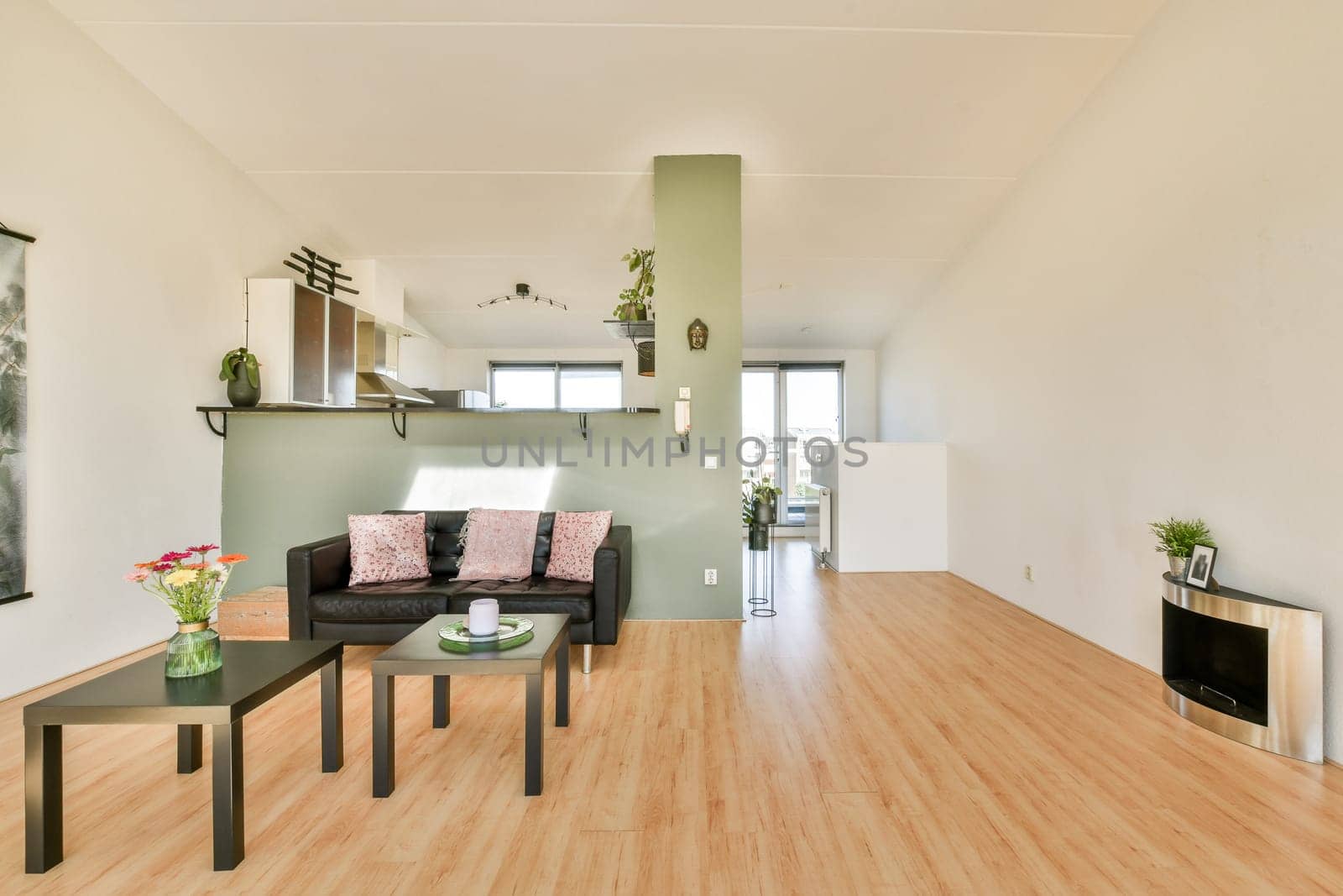 A spacious and modern living room featuring a minimalist aesthetic with natural light, stylish furniture, and decorative elements. The design emphasizes simplicity and comfort.
