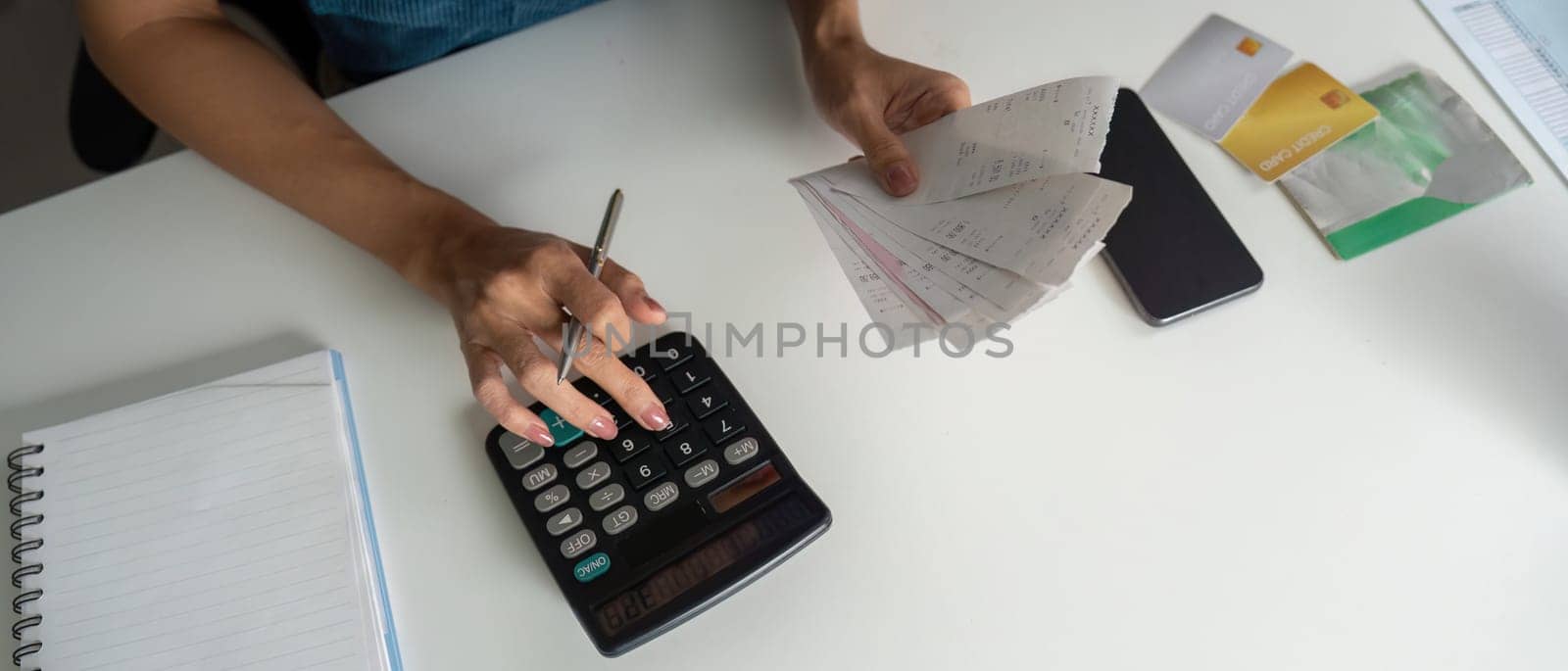 An attentive individual is managing their finances, holding multiple receipts, and calculating bills to maintain a stable budget.