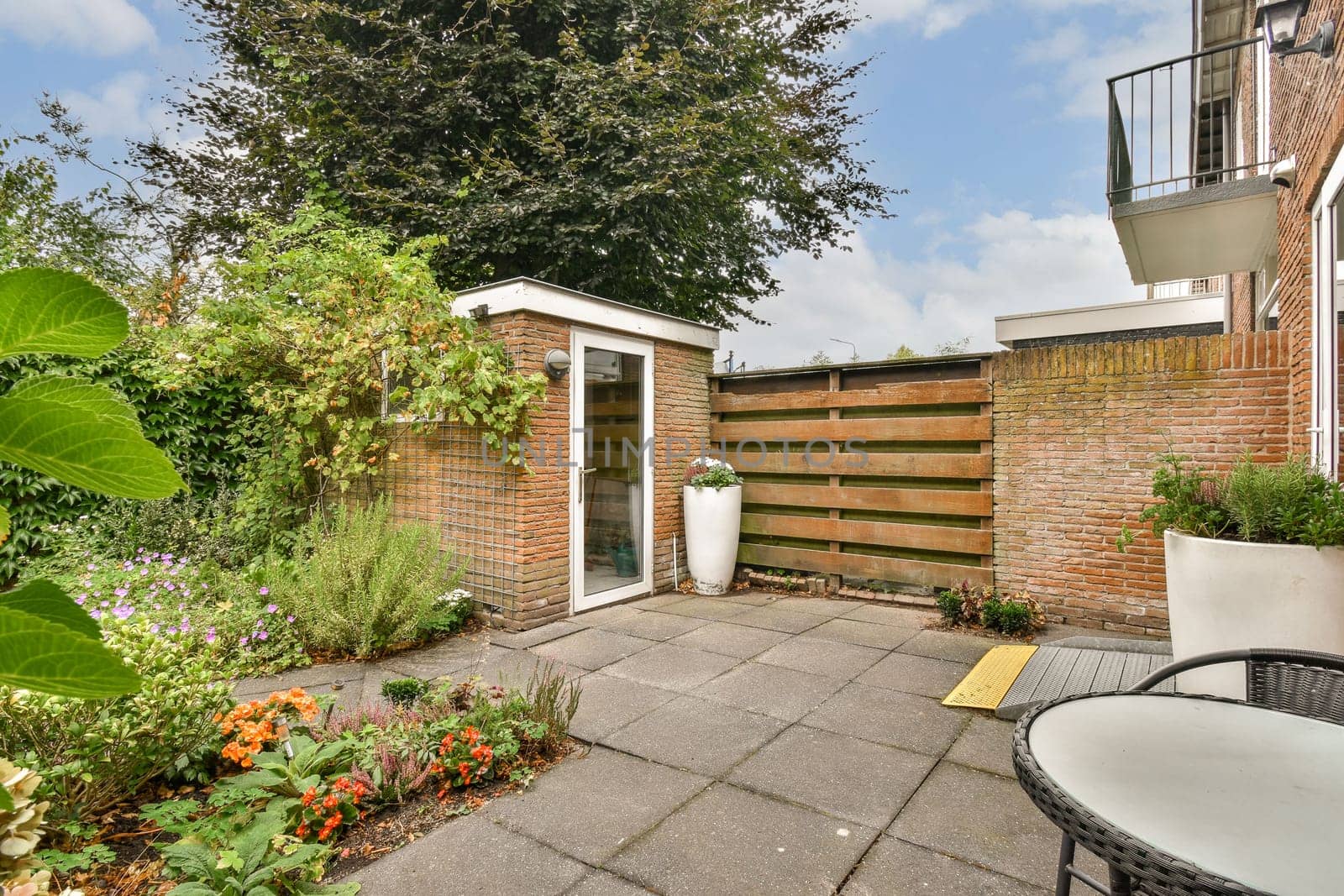A serene garden patio featuring lush greenery, decorative plants, and a cozy seating area, perfect for relaxation and outdoor enjoyment.