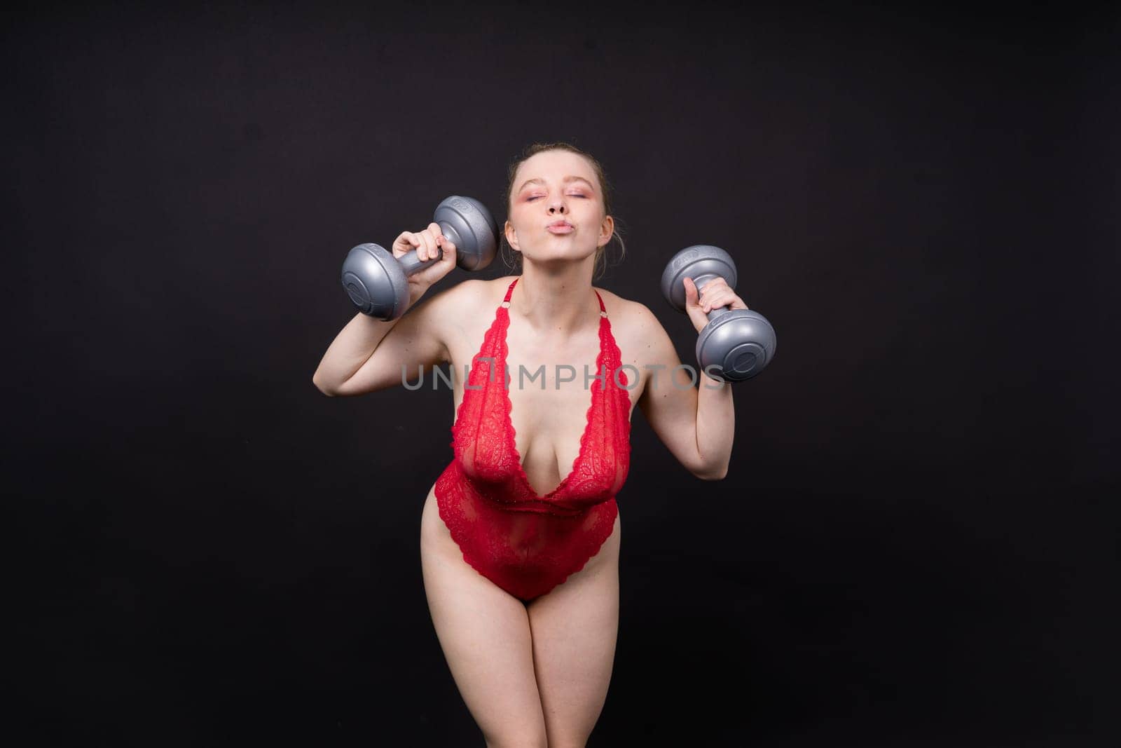 Smiling young plump fitness sporty seductive woman working out doing exercise with a dumbbells