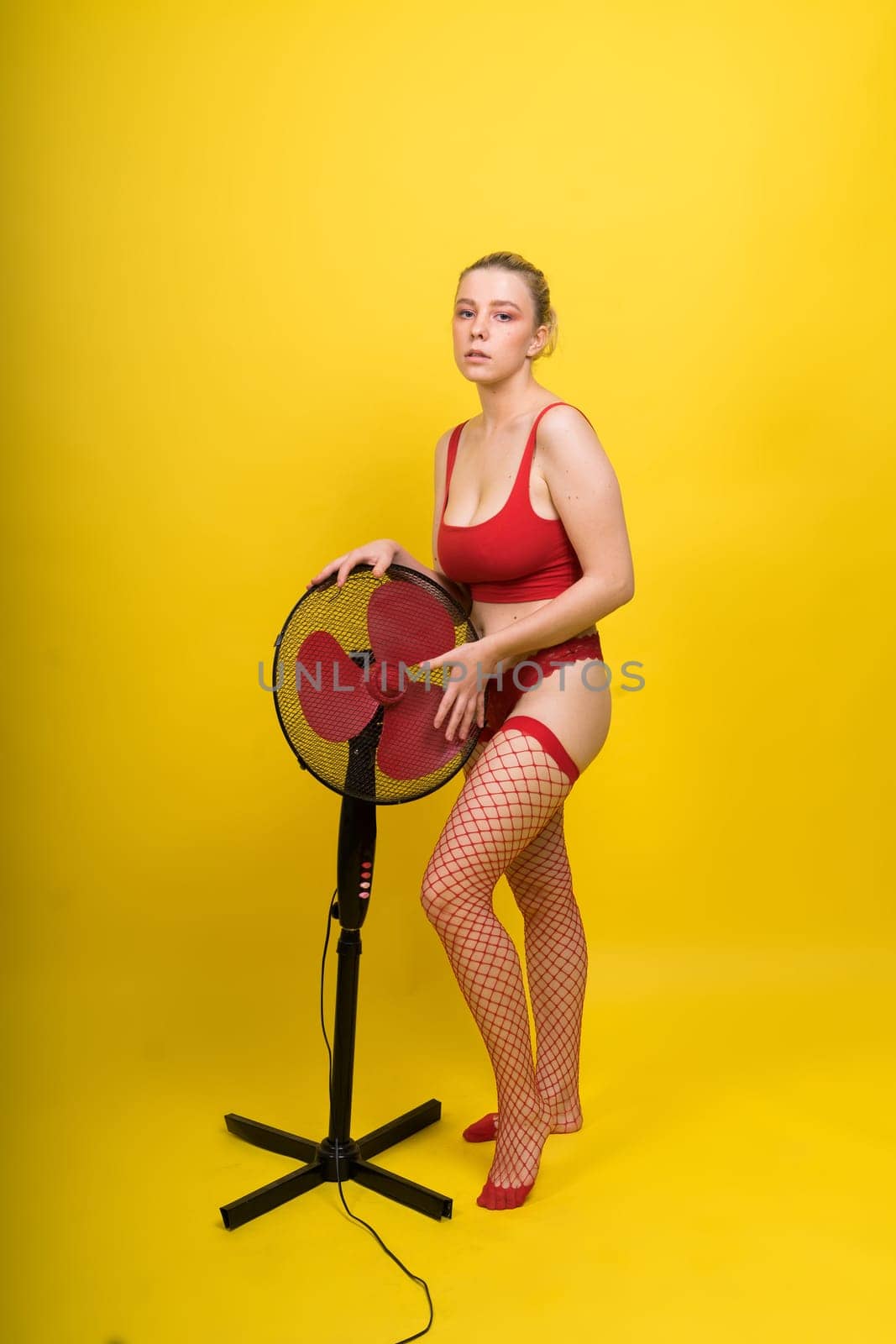 Young seductive female model posing in a lingerie with working fan
