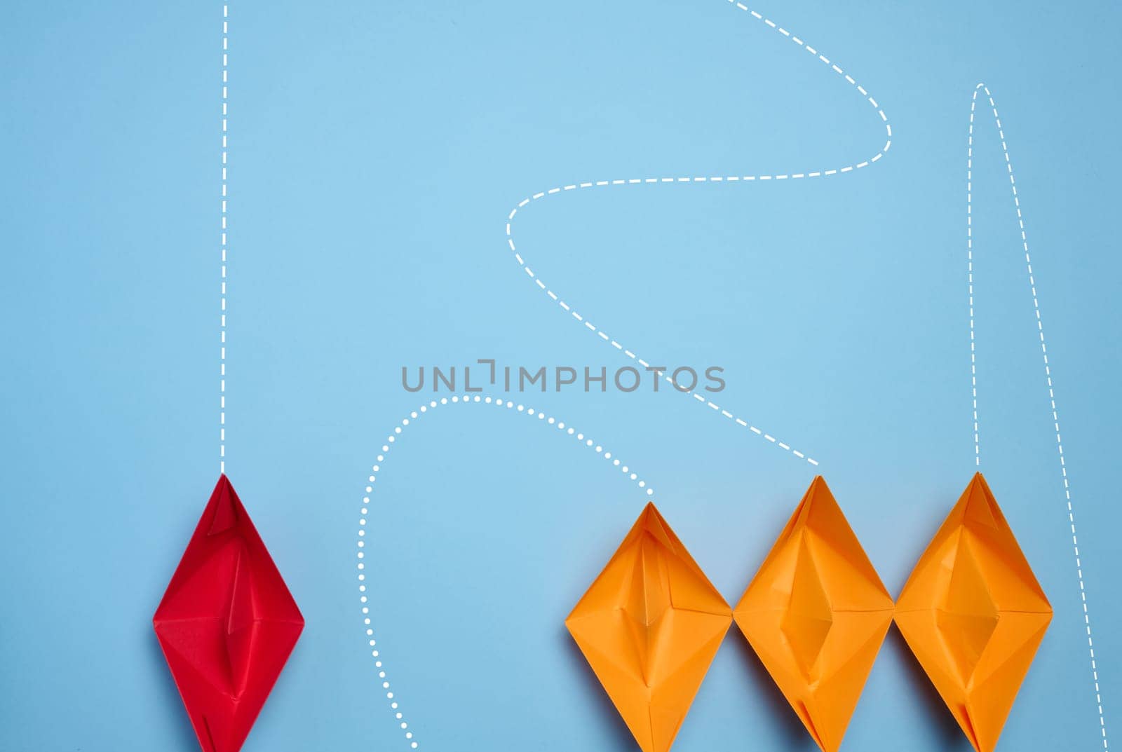 Paper boats on a blue background, representing the concept of competition in business, teamwork, and innovative approaches for achieving goals