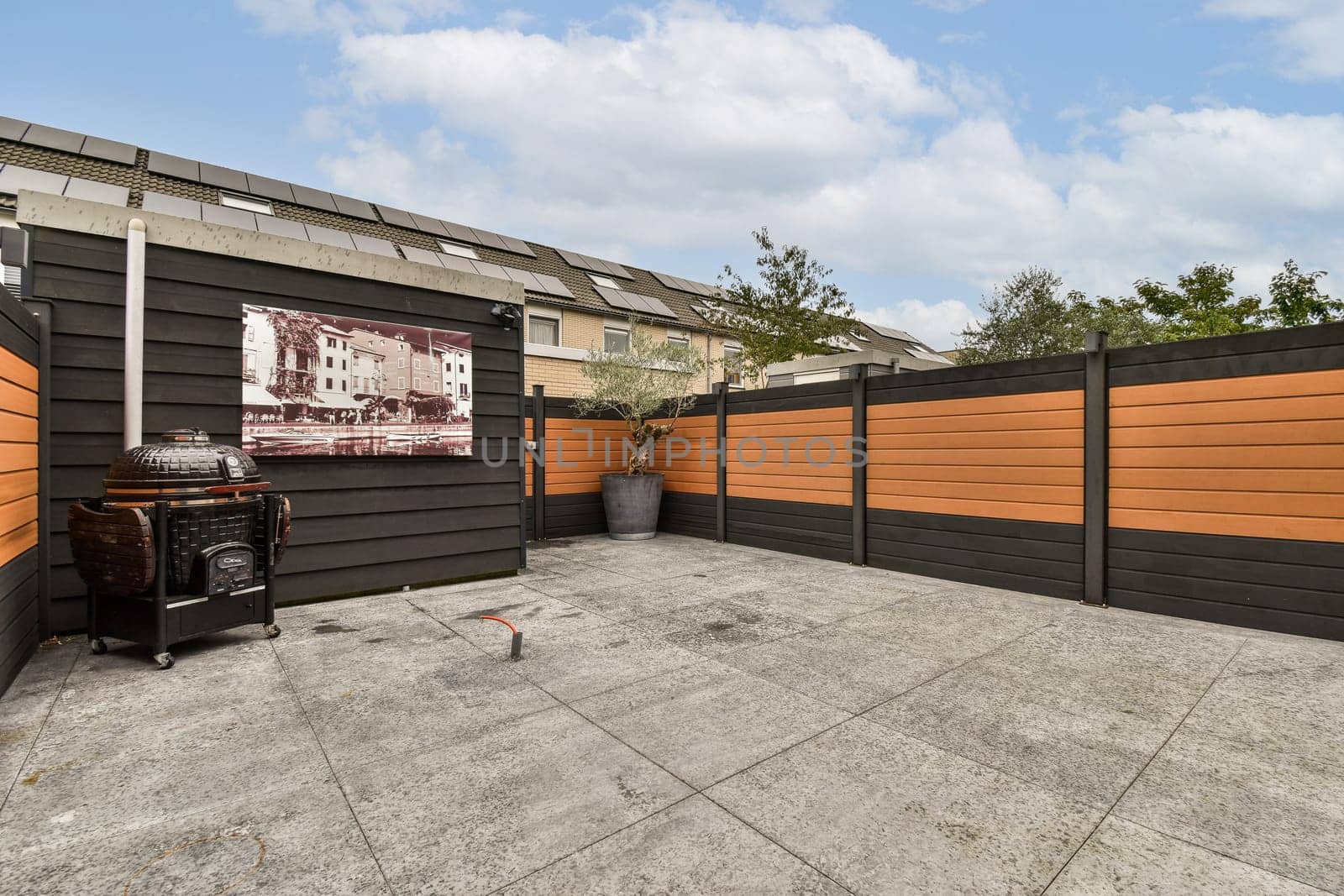 A stylish outdoor patio featuring modern design elements, including a decorative wall with artwork and contemporary furniture. The setting is serene and inviting.