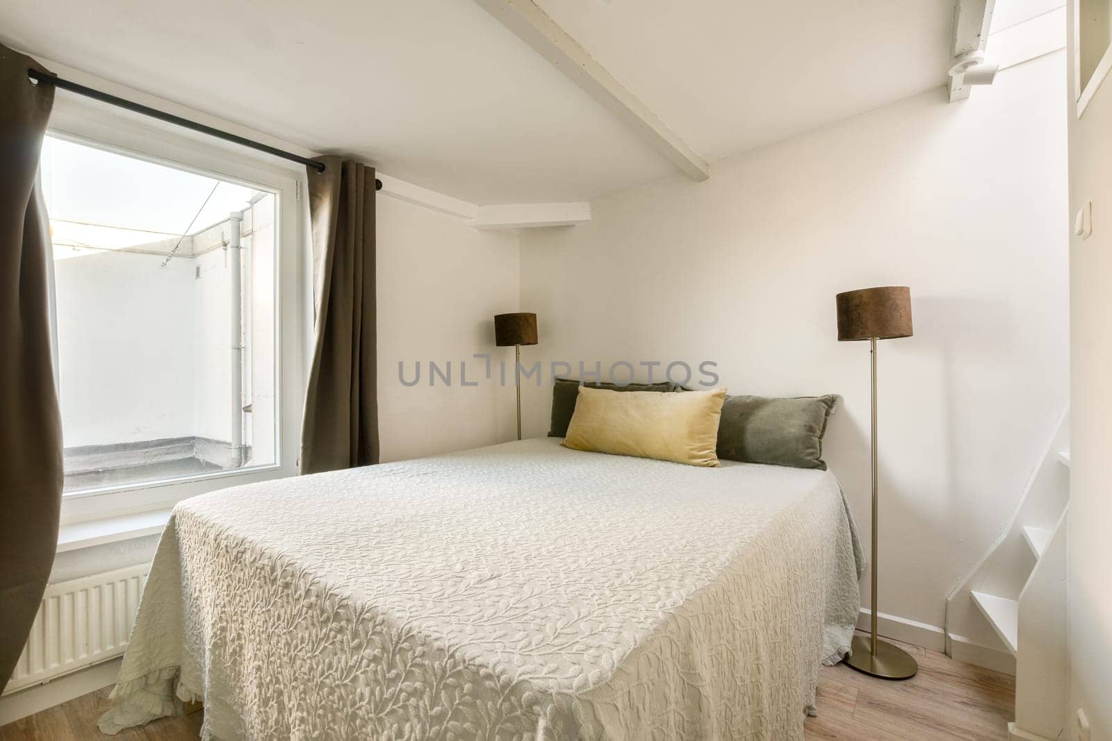 A serene bedroom featuring a comfortable bed and large window that invites natural light, creating a warm and inviting atmosphere.