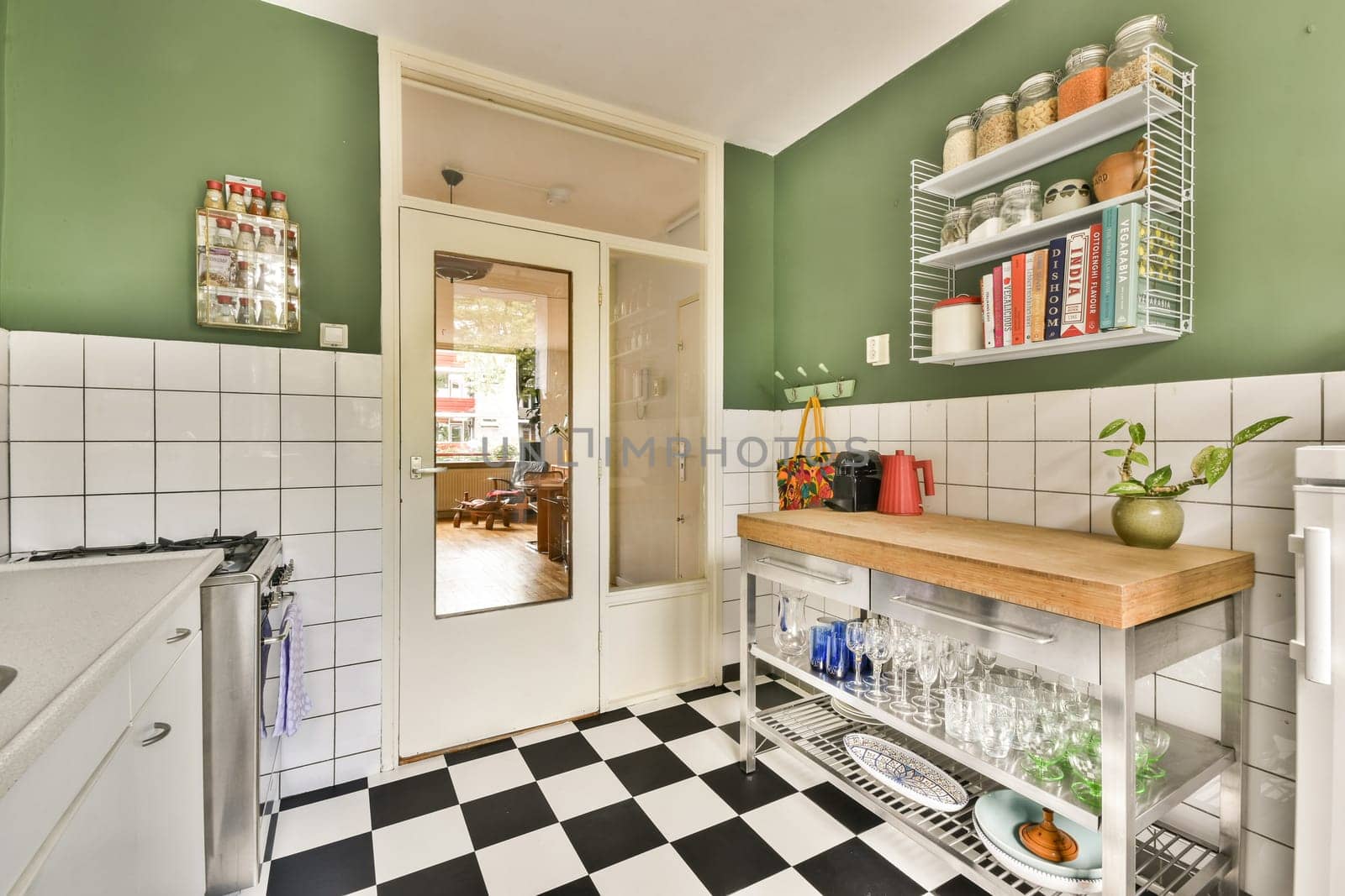Stylish kitchen featuring sleek furnishings, vibrant green walls, and organized shelves displaying various kitchenware. A blend of modern aesthetics and functionality.