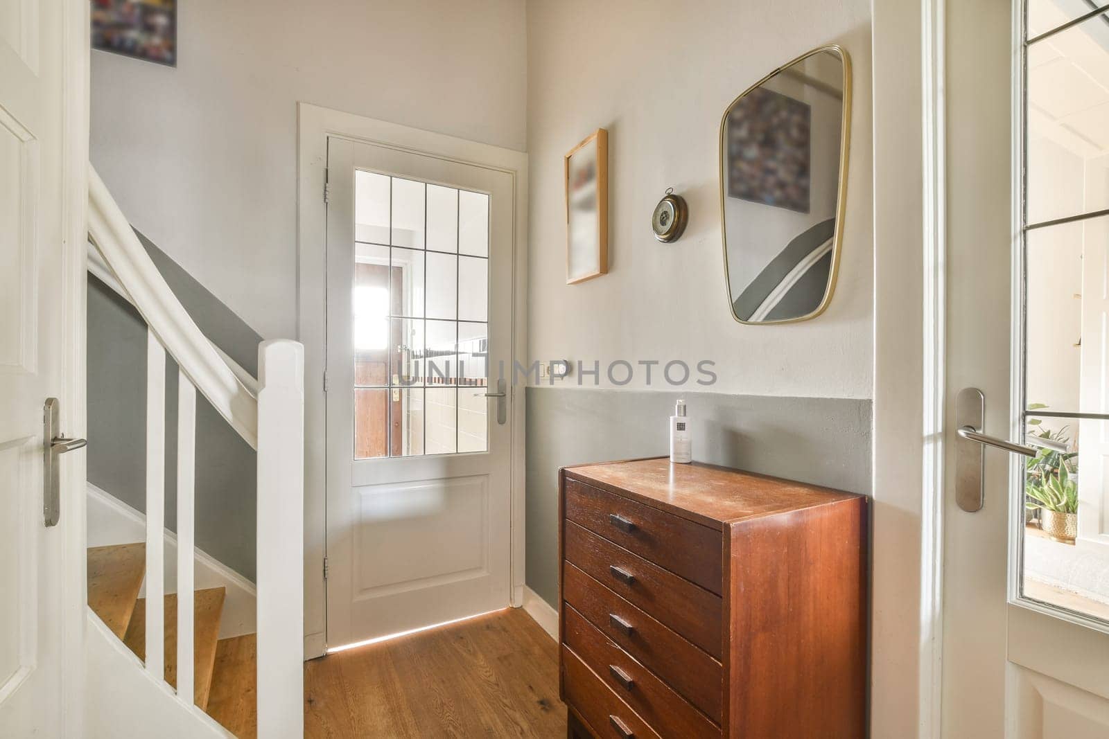 A well-lit hallway showcasing a blend of modern design and classic wooden furniture, featuring a staircase and decorative elements, creating an inviting atmosphere.