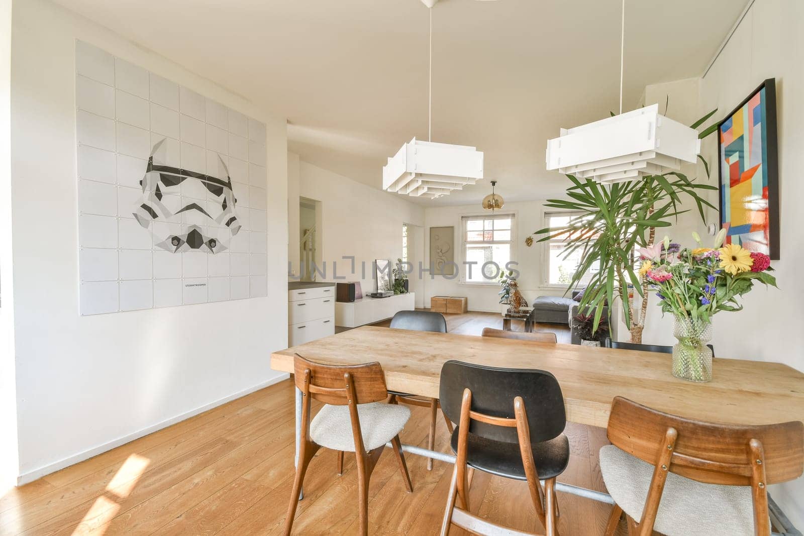 A spacious interior design featuring modern furniture, a decorative wall art piece, and vibrant flowers creating a welcoming atmosphere.