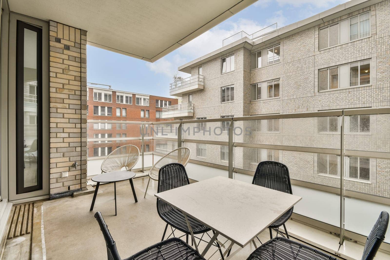 Stylish balcony featuring a minimalistic design with a concrete floor, modern furniture, and a view of adjacent buildings, perfect for relaxation.