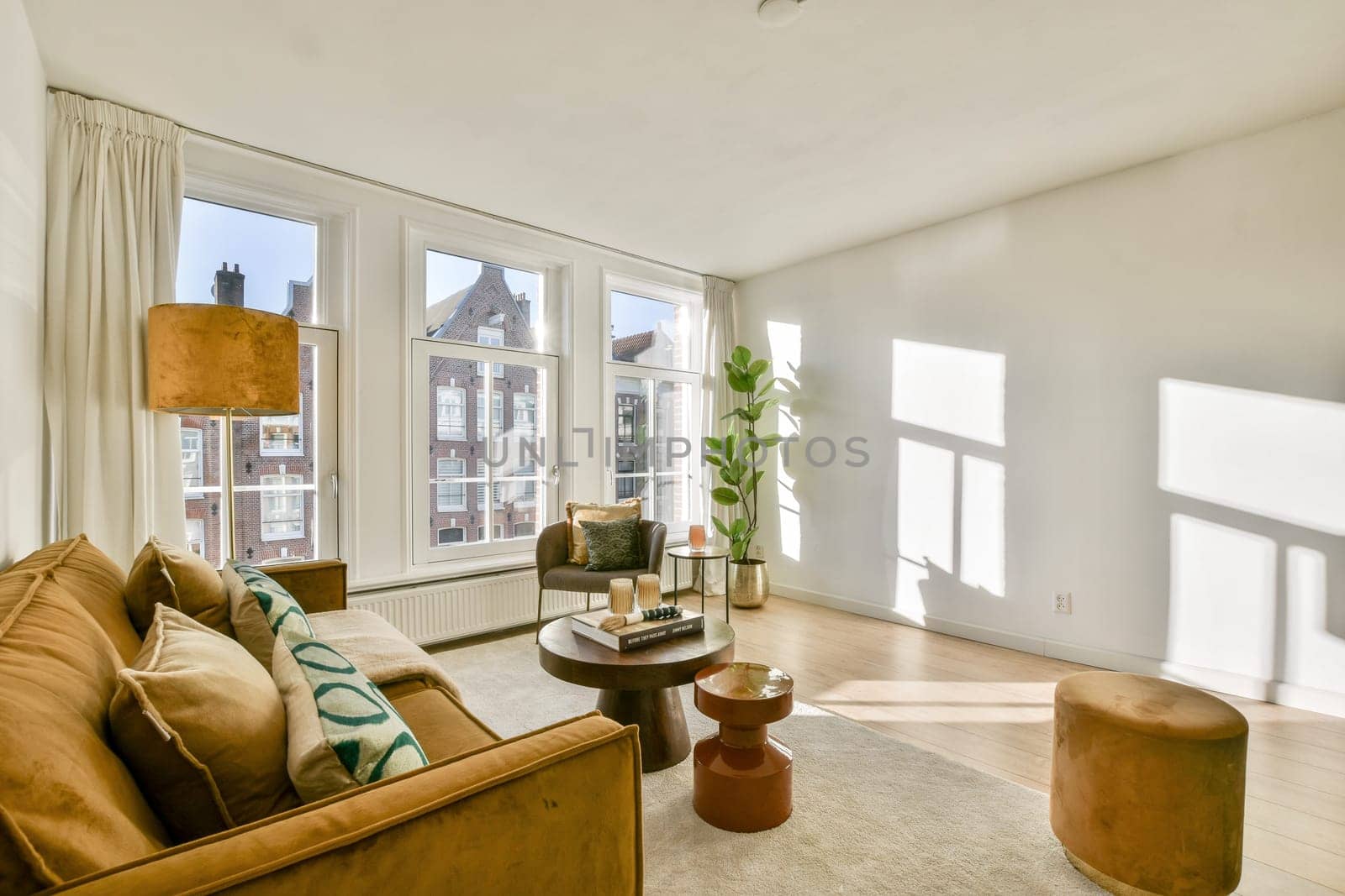 A stylish living room featuring a cozy sofa, modern decor, and abundant natural light pouring through large windows, enhancing the welcoming atmosphere.