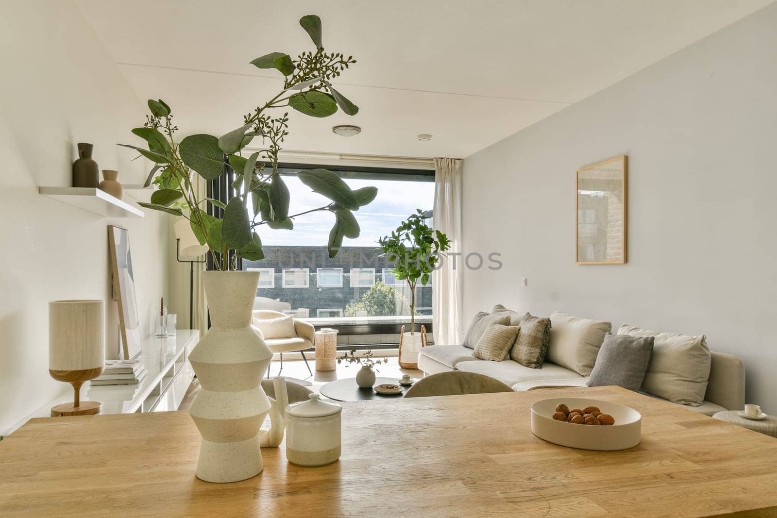 A stylish living room showcasing minimalist decor with a focus on natural elements. The space features plants, soft furnishings, and a spacious layout that promotes tranquility.