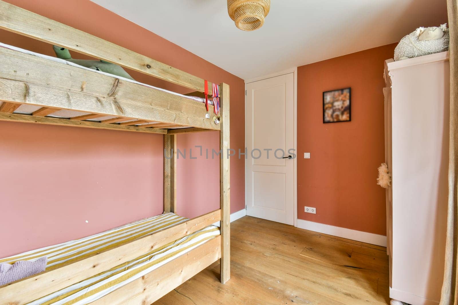 A warm, inviting bedroom featuring a wooden bunk bed against a soft pink wall, creating a serene atmosphere perfect for relaxation.