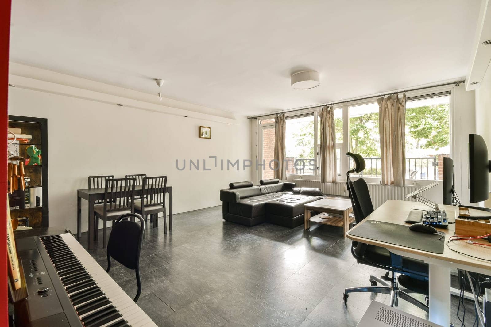 A stylish and spacious living room featuring natural light, modern furniture, and a creative workspace, perfect for relaxation and productivity.