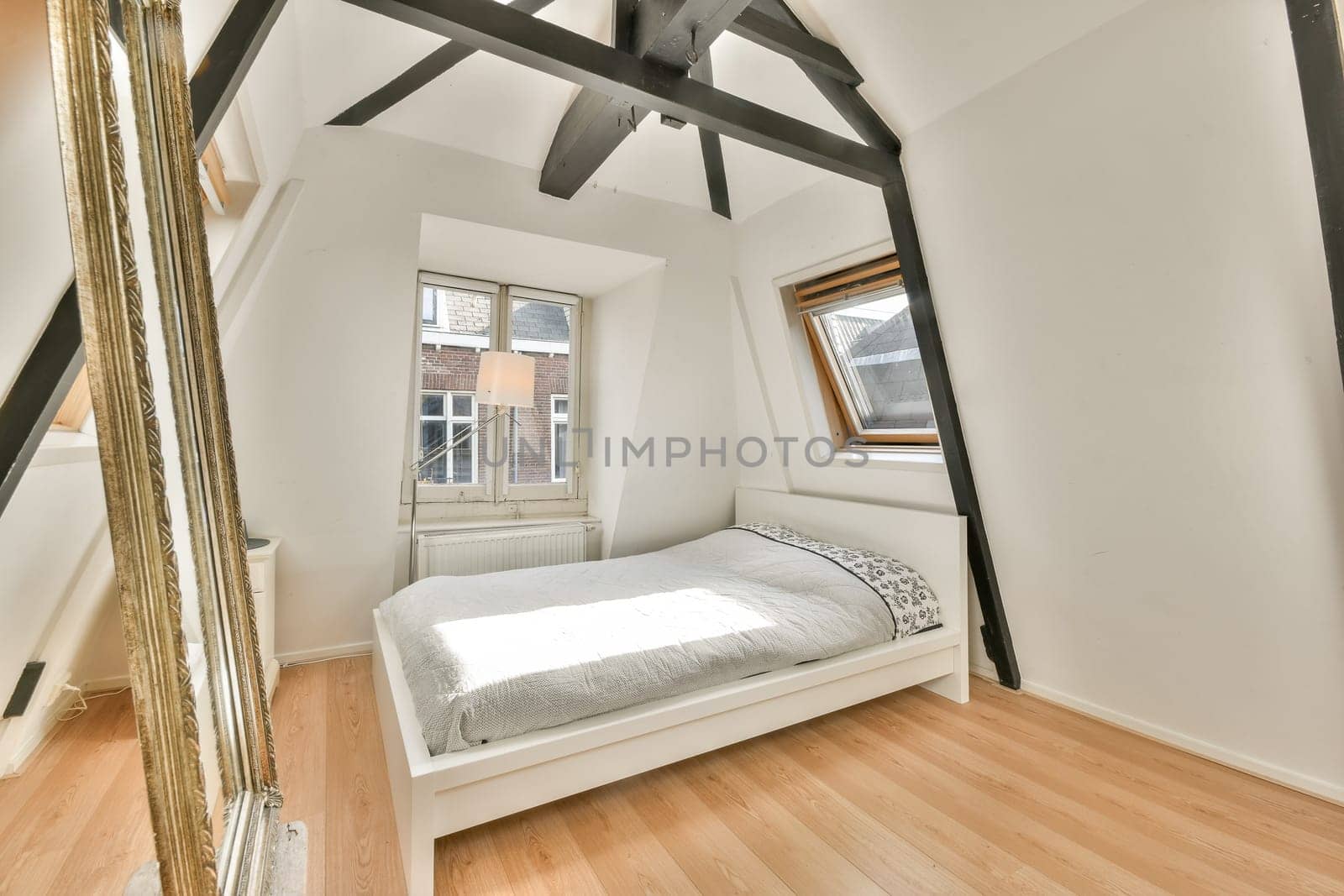 A bright and airy modern bedroom featuring minimalist decor, wooden floors, and large windows enhancing natural light with a cozy bed setup.
