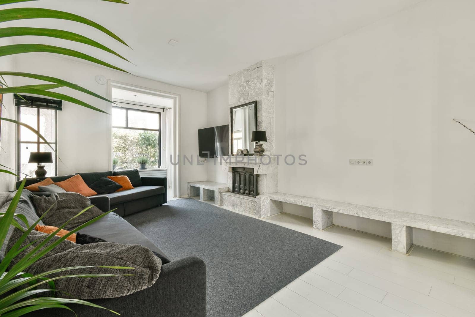 A spacious and contemporary living room featuring a stylish gray sofa, fireplace, and elegant furnishings designed for comfort and relaxation.