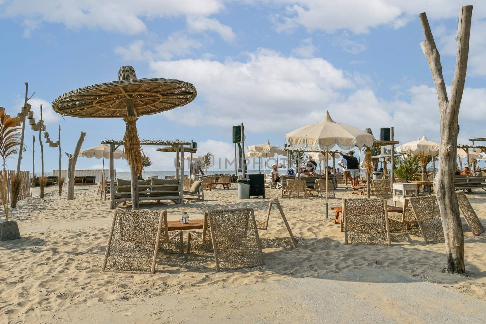 A serene beachside cafe featuring umbrellas, lounge chairs, and beautiful sandy surroundings, perfect for a relaxing day by the ocean.