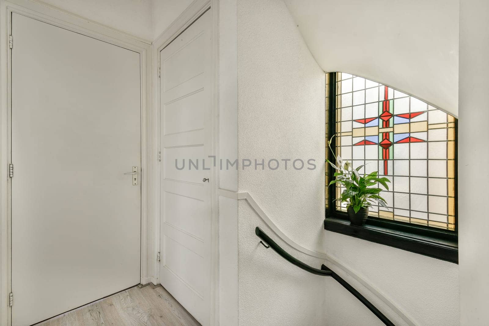 A well-designed interior featuring a stained glass window, a serene ambiance, and soft natural light illuminating the staircase area.