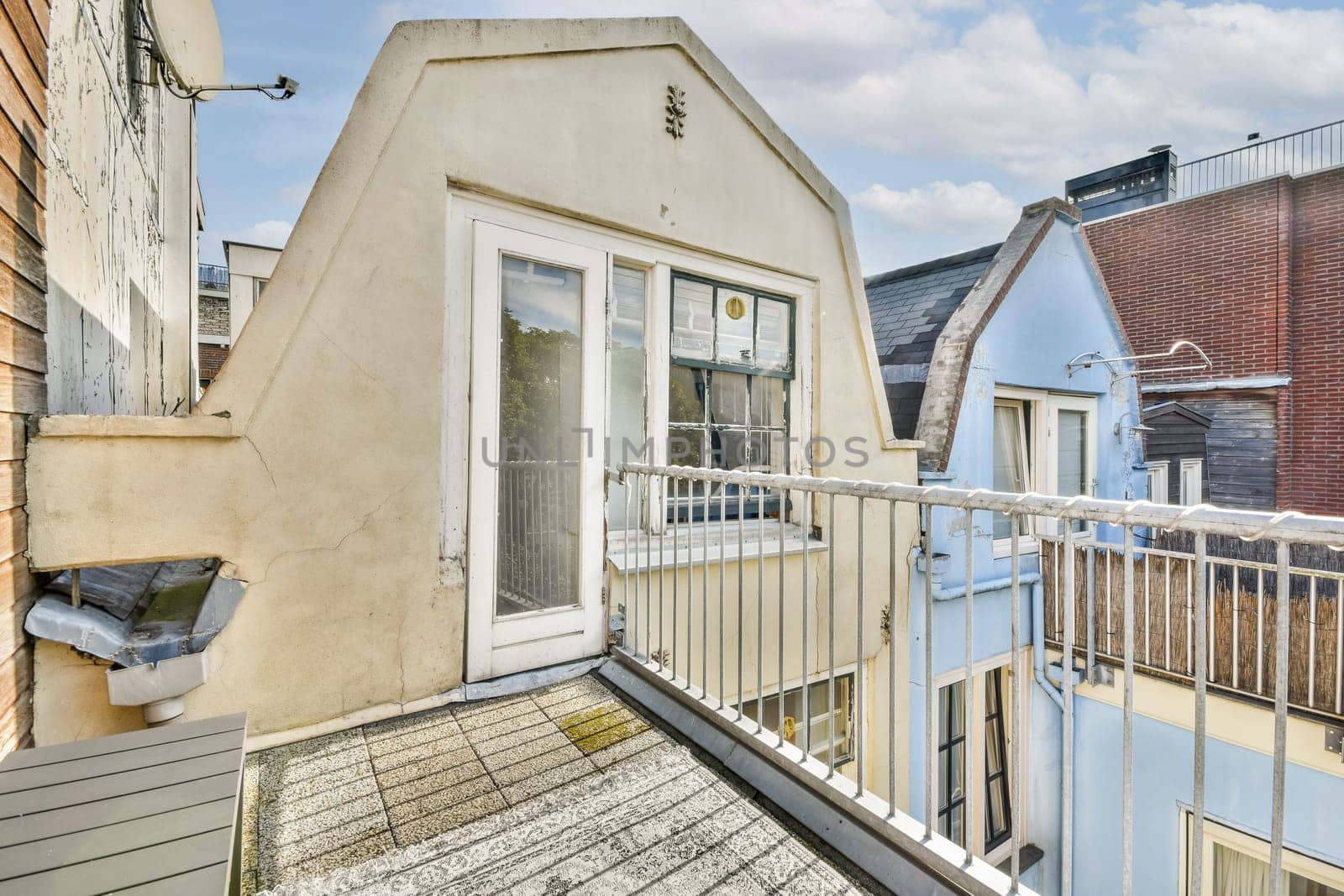 A picturesque glimpse of a cozy balcony set against a backdrop of urban rooftops under a serene sky, perfect for relaxation or morning coffee.