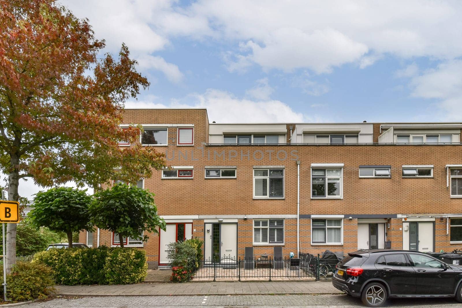 A modern residential building featuring a well-maintained facade and lush greenery in front, creating an inviting atmosphere. Perfect for showcasing contemporary architecture.