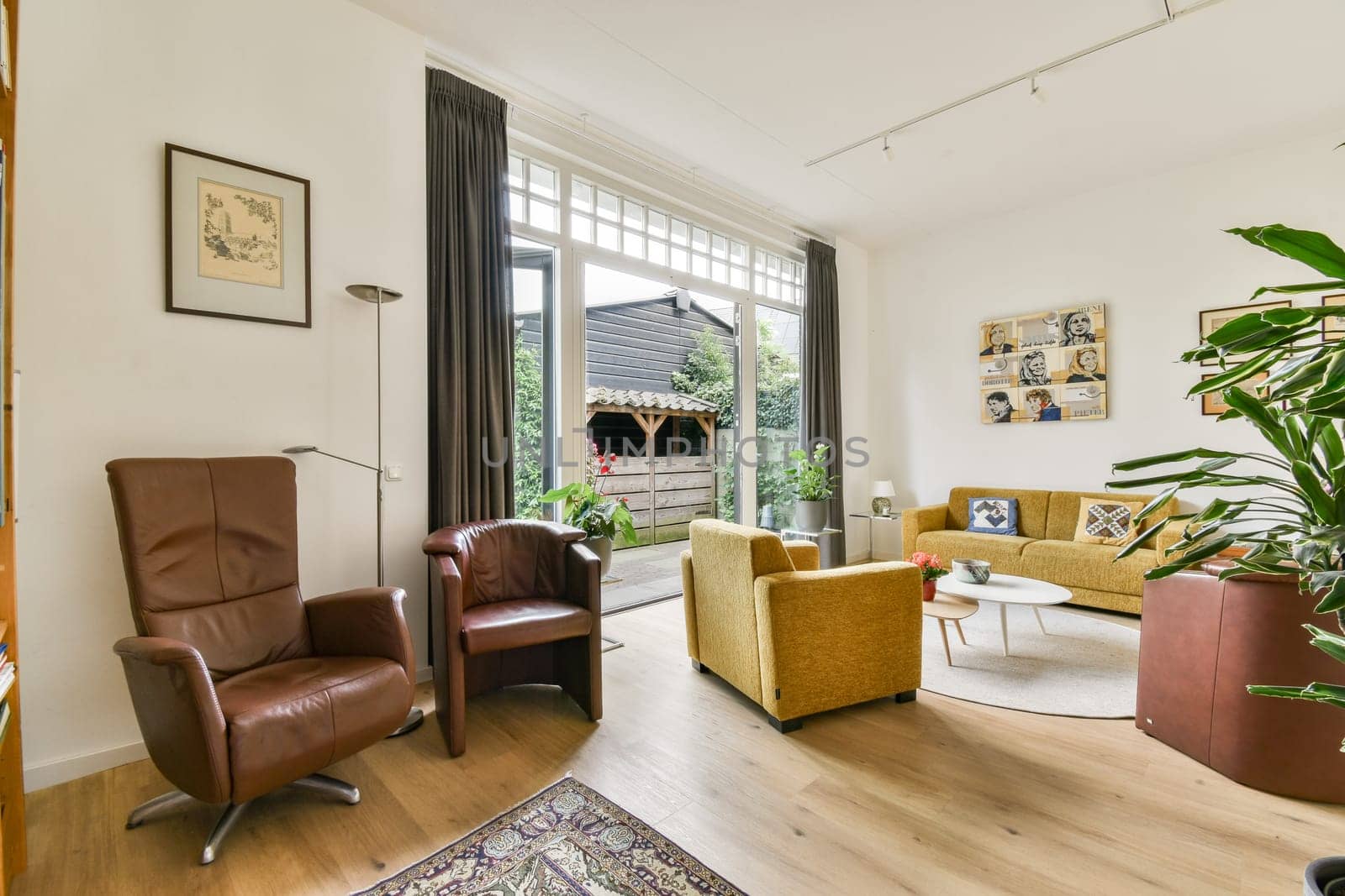 A modern living room featuring stylish furniture and large windows that let in ample natural light, creating a warm and inviting atmosphere.