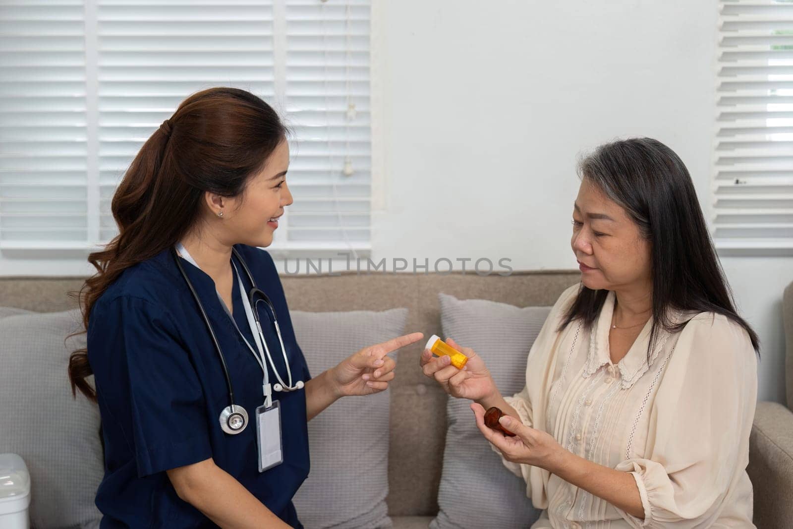 In a friendly home setting, a nurse provides essential medication advice to an elderly woman, ensuring her health needs are met with care.