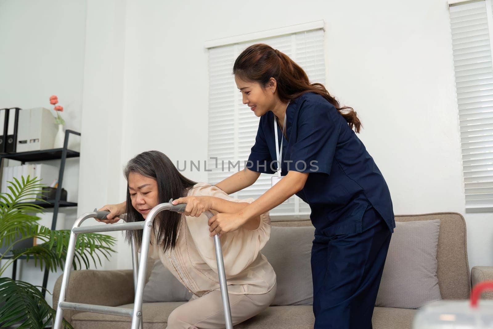 A caregiver gently encourages an elderly woman as she uses her walker, emphasizing safety and confidence during mobility.