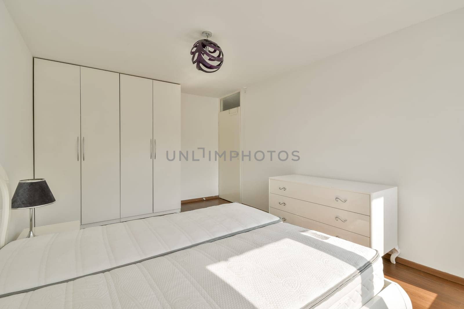 A contemporary bedroom featuring a simple design with a bed, wardrobe, and nightstand, highlighting neutral colors and clean lines for a serene atmosphere.
