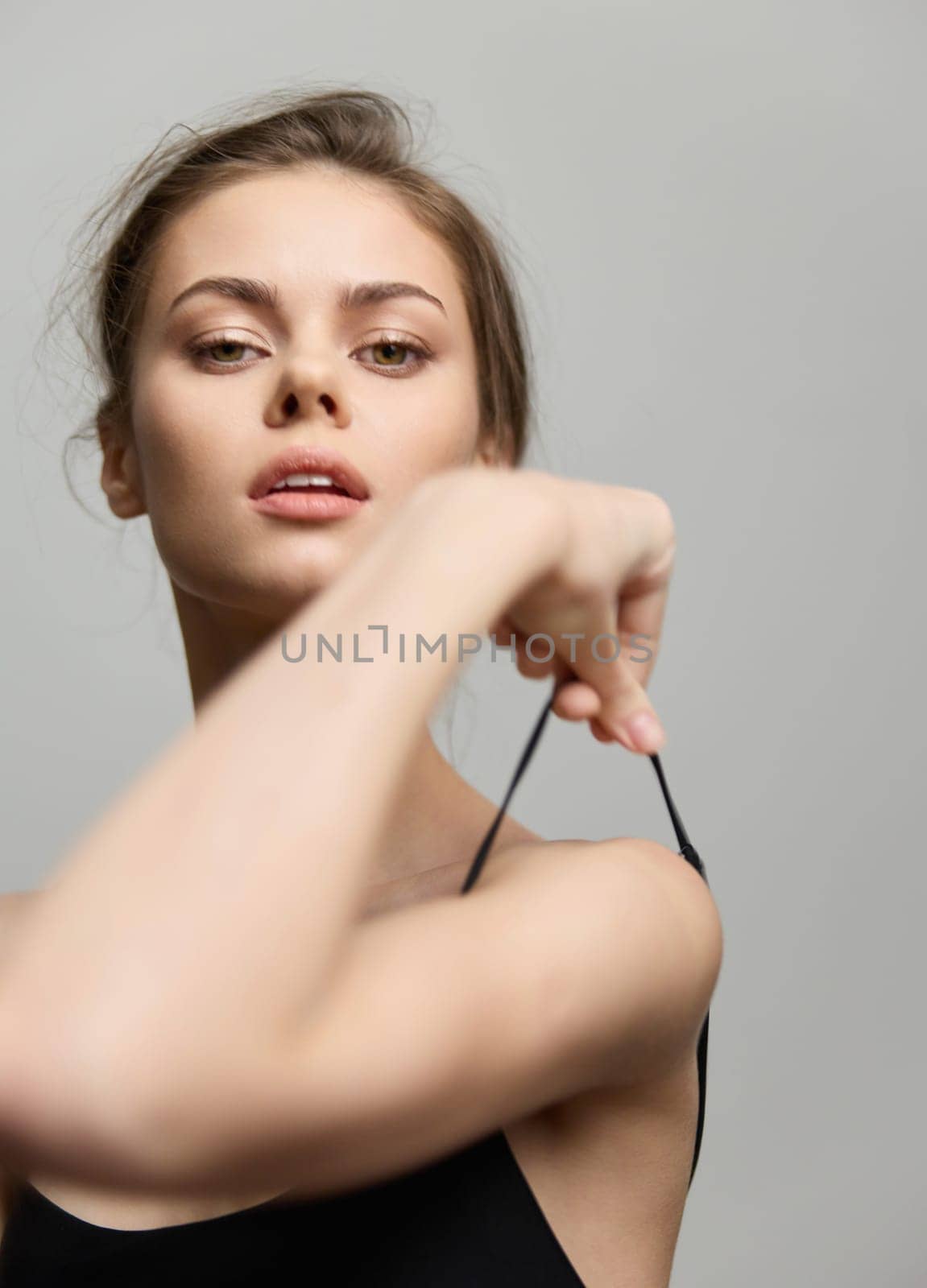Stylish woman displaying a bold expression while adjusting her outfit, reflecting modern beauty and self-assurance. Concept of fashion and empowerment.