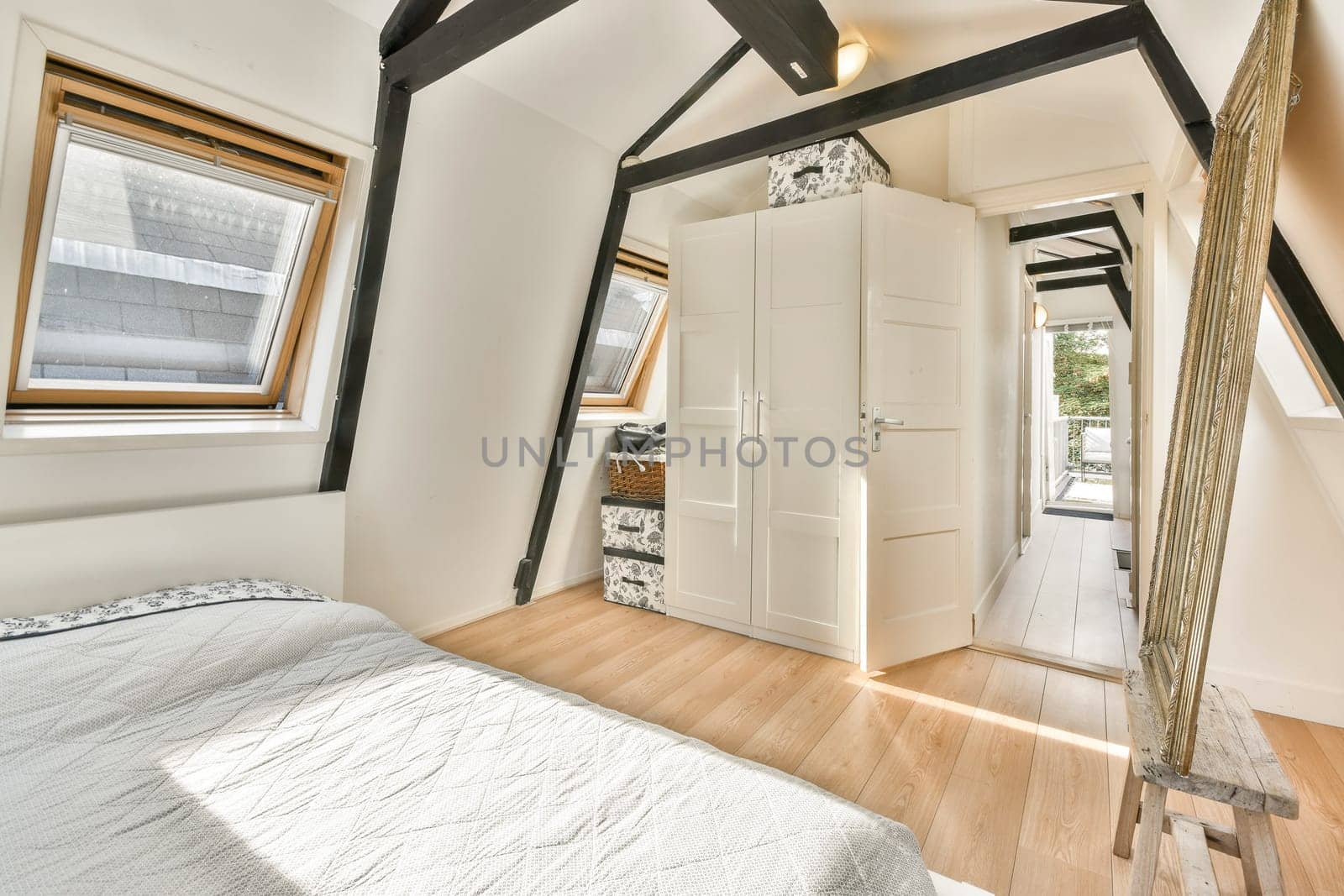 A sleek modern bedroom interior featuring wooden flooring, large windows, and minimalist decor enhancing natural light and spaciousness.