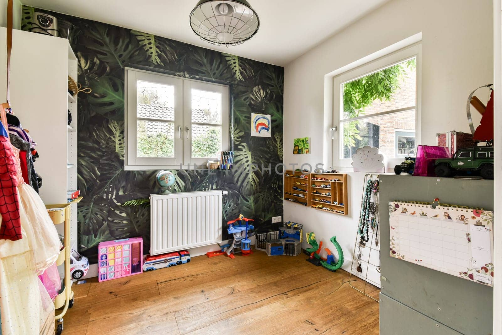 A vibrant children's room featuring lush tropical wallpaper, playful decor, and wooden flooring, creating a welcoming and fun space for kids.