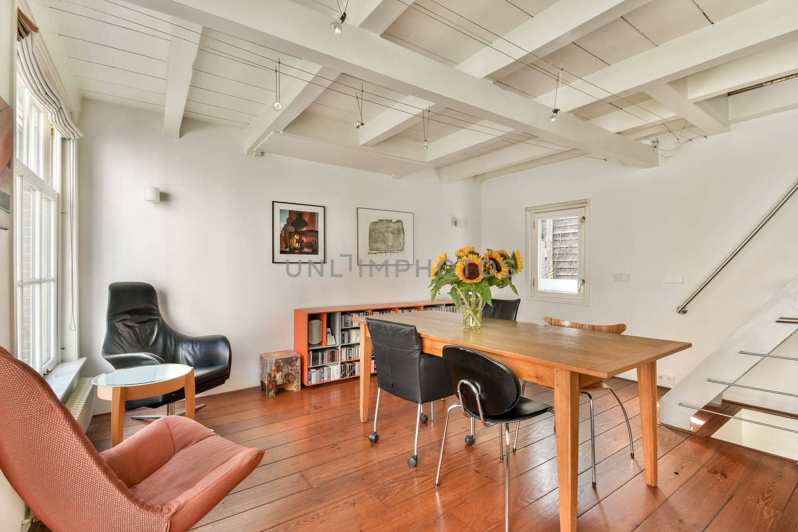 A well-lit modern interior featuring a wooden table, stylish chairs, and vibrant sunflowers adds freshness to the warm ambiance, showcasing contemporary design elements.
