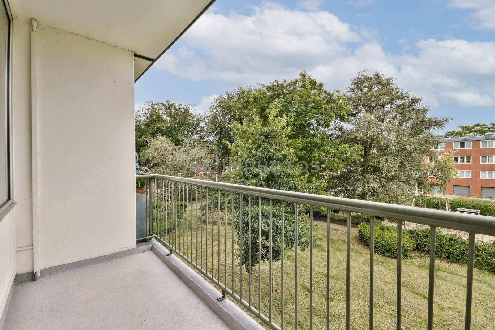 A spacious balcony overlooking a vibrant landscape filled with lush trees and manicured gardens. A tranquil outdoor space inviting relaxation.