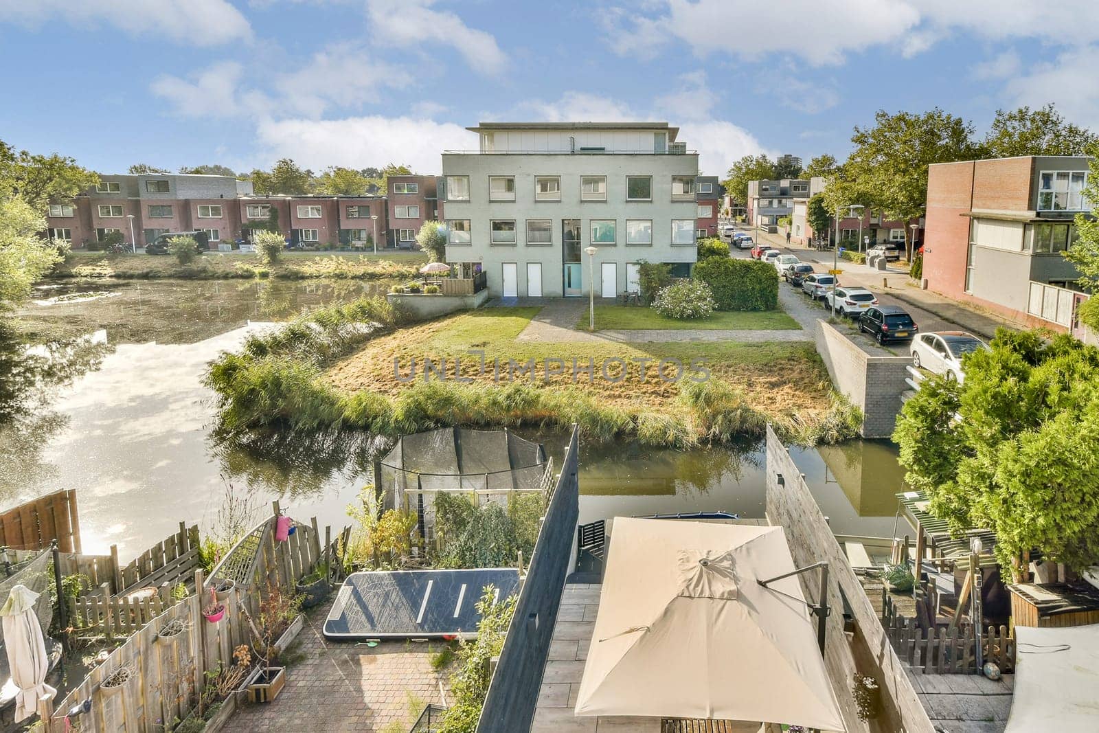 A scenic view showcasing modern buildings alongside a serene waterway, framed by greenery and landscaped areas, capturing the essence of urban living.