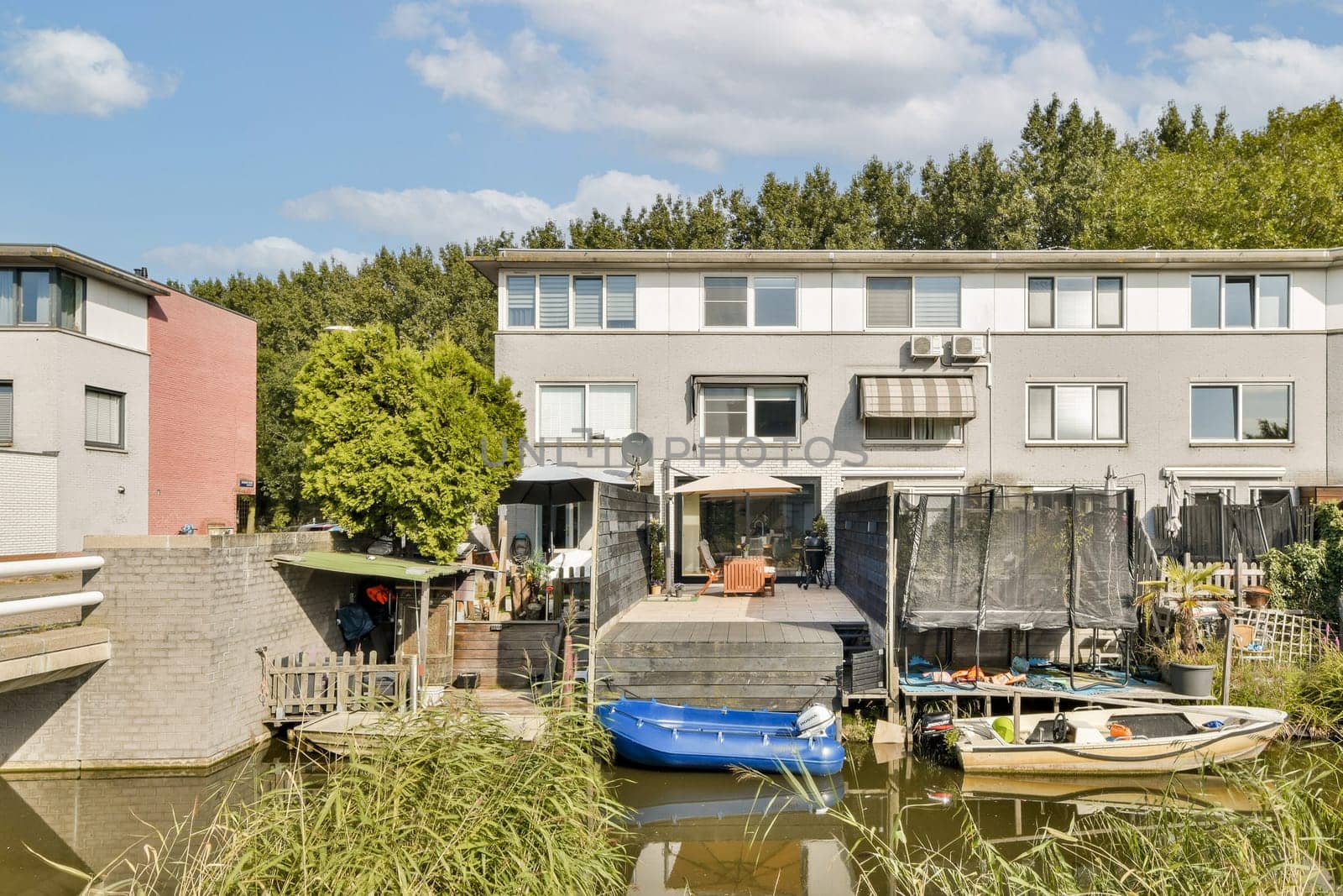 Scenic view of riverside houses showcasing modern architecture alongside boats. Lush greenery enhances the peaceful ambiance in this residential area.