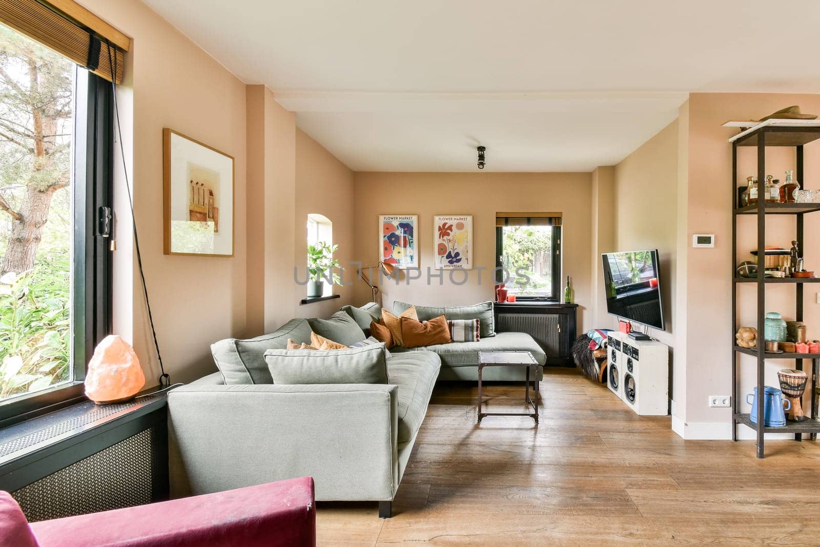 A stylish modern living room featuring comfortable seating, large windows with greenery, and decorative shelves, blending comfort and elegance.