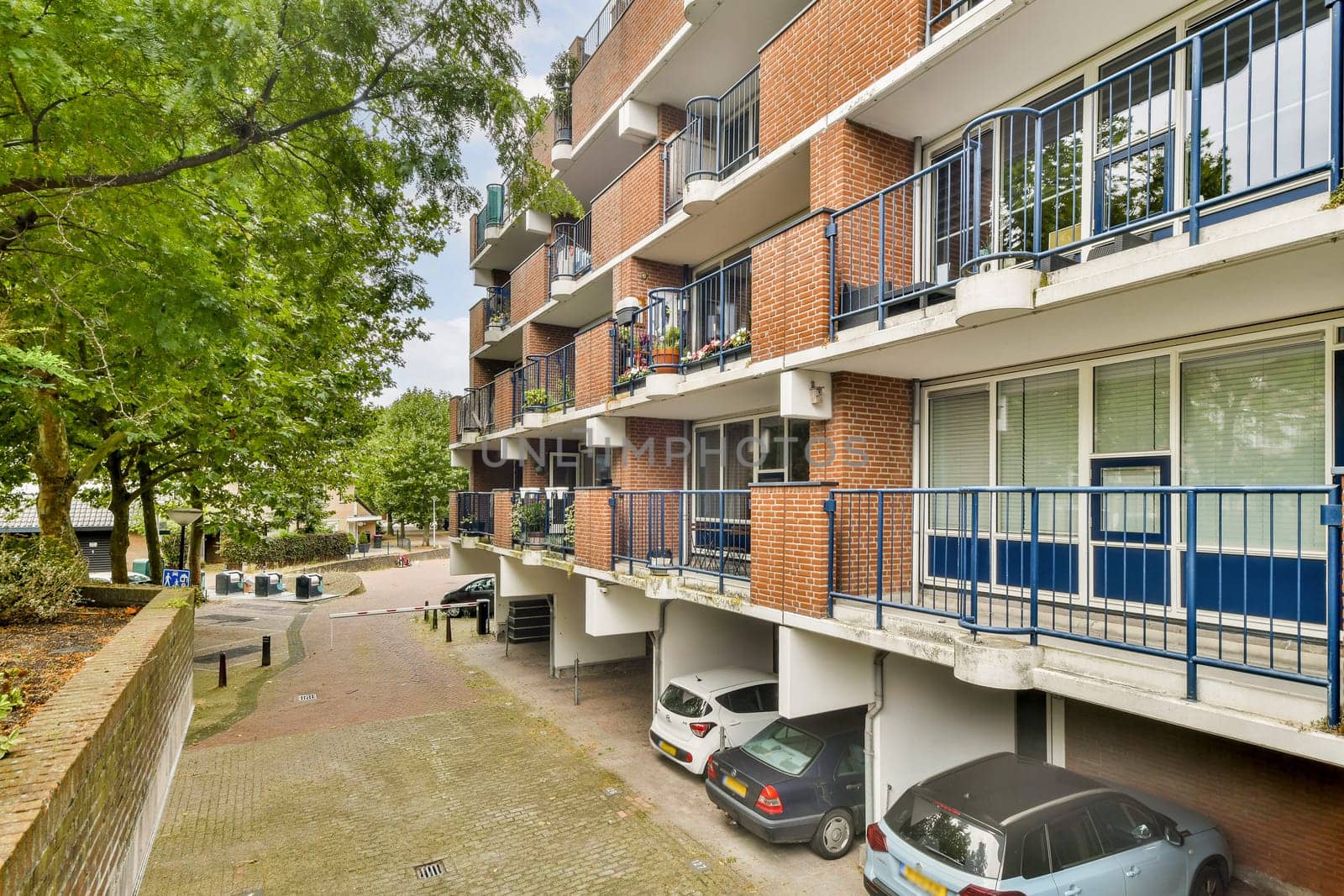 A view of a contemporary multi-story apartment building featuring multiple balconies and landscaped greenery, showcasing urban living and architecture.