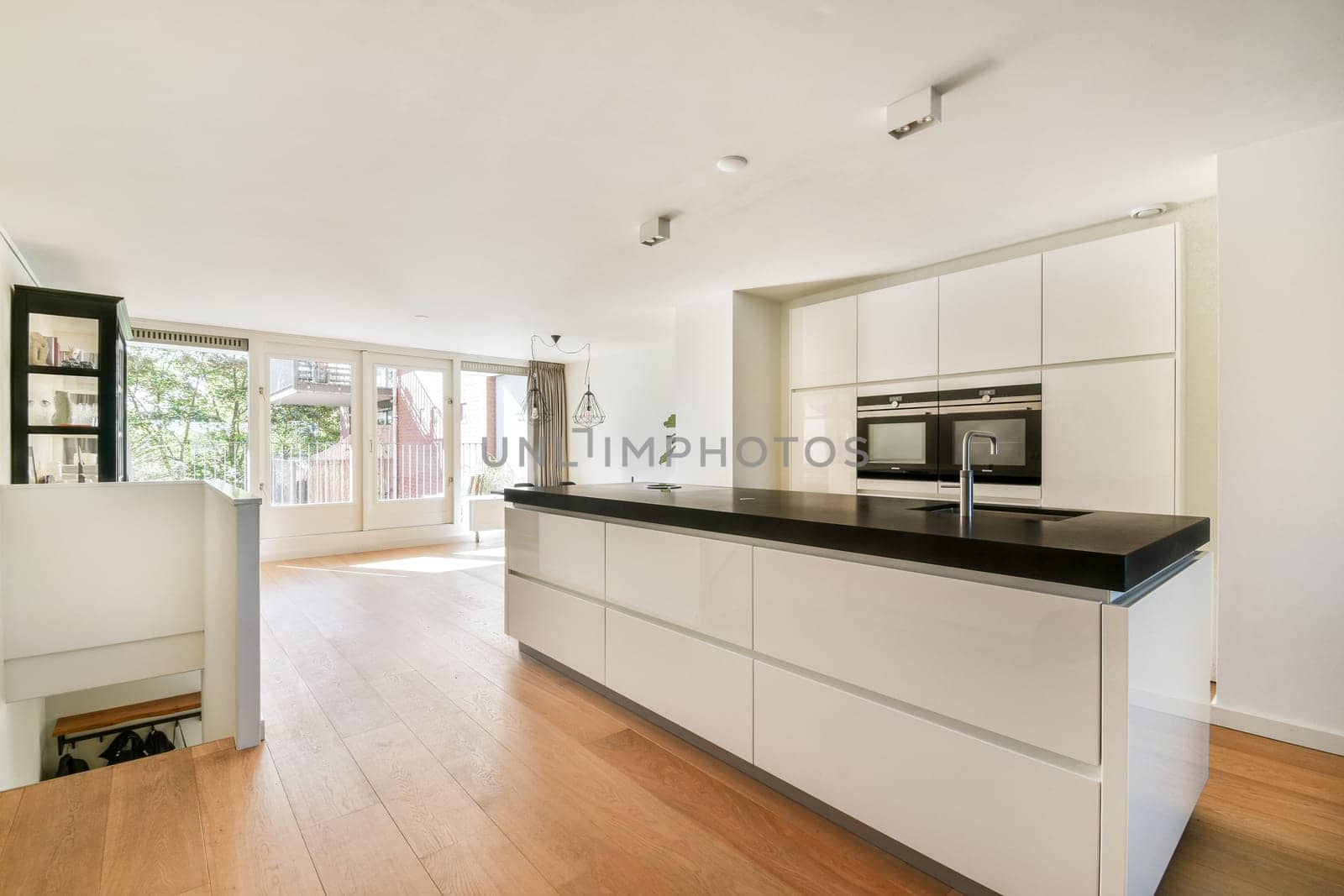 A sleek, modern kitchen featuring light-colored cabinetry and a spacious design illuminated by natural light streaming through large windows.