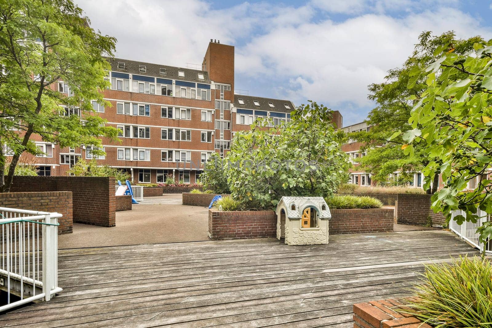 A contemporary residential building featuring a blend of brick and glass, framed by lush greenery and an inviting pathway for residents.