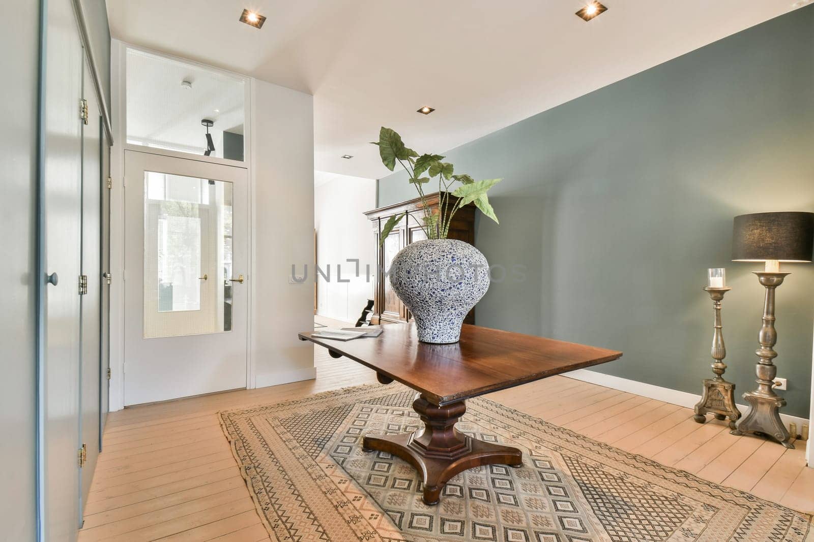 A stylish interior space featuring a wooden table with an elegant decorative vase, complemented by soft lighting and calming wall colors.