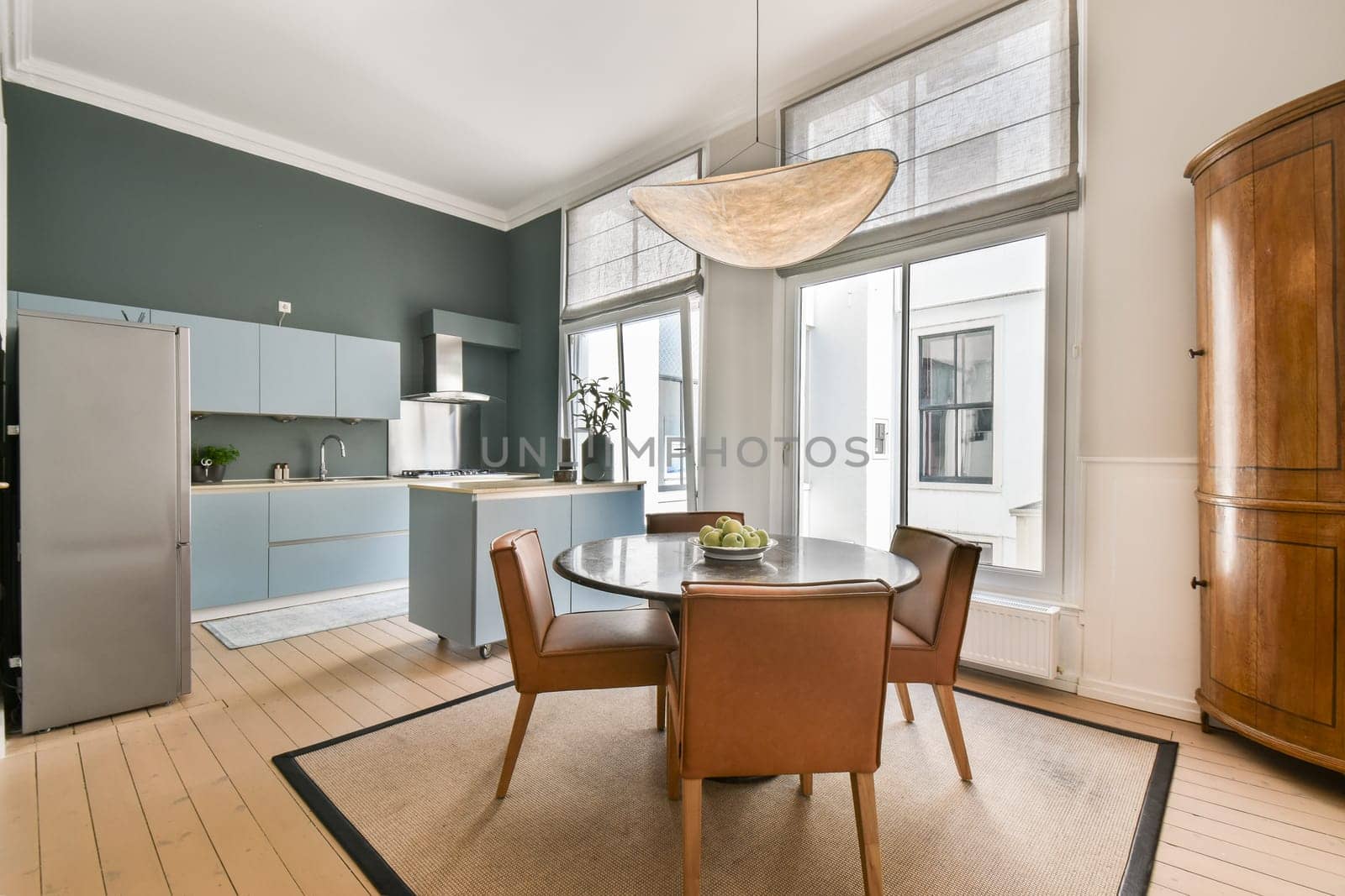 Stylish modern kitchen featuring a sleek design, a round dining table, contemporary chairs, and large windows allowing natural light to fill the space.