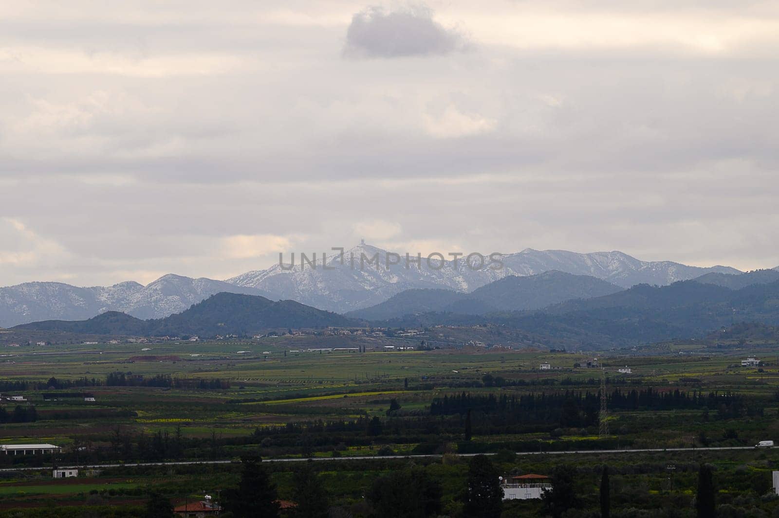 Majestic mountains loom in the background, partially shrouded in clouds, while a lush green landscape stretches below. The atmosphere is calm and serene, inviting reflection.