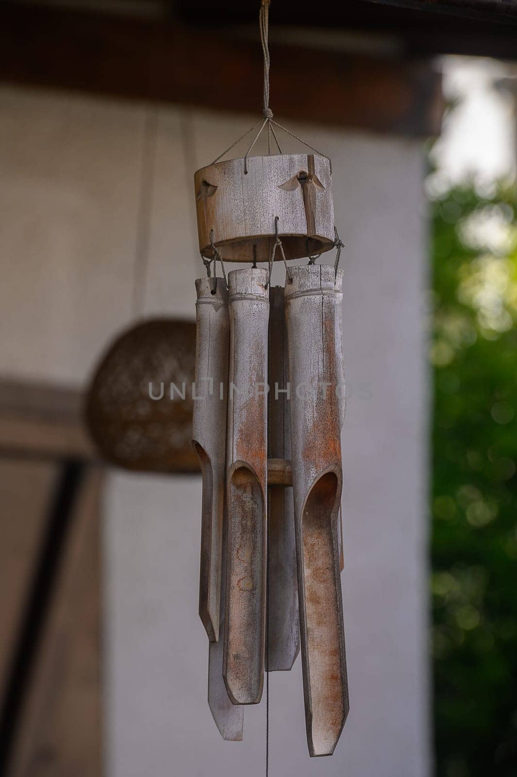 A serene garden features beautifully crafted wind chimes hanging from a wooden structure, reflecting sunlight as they sway softly in the warm seasonal breeze.