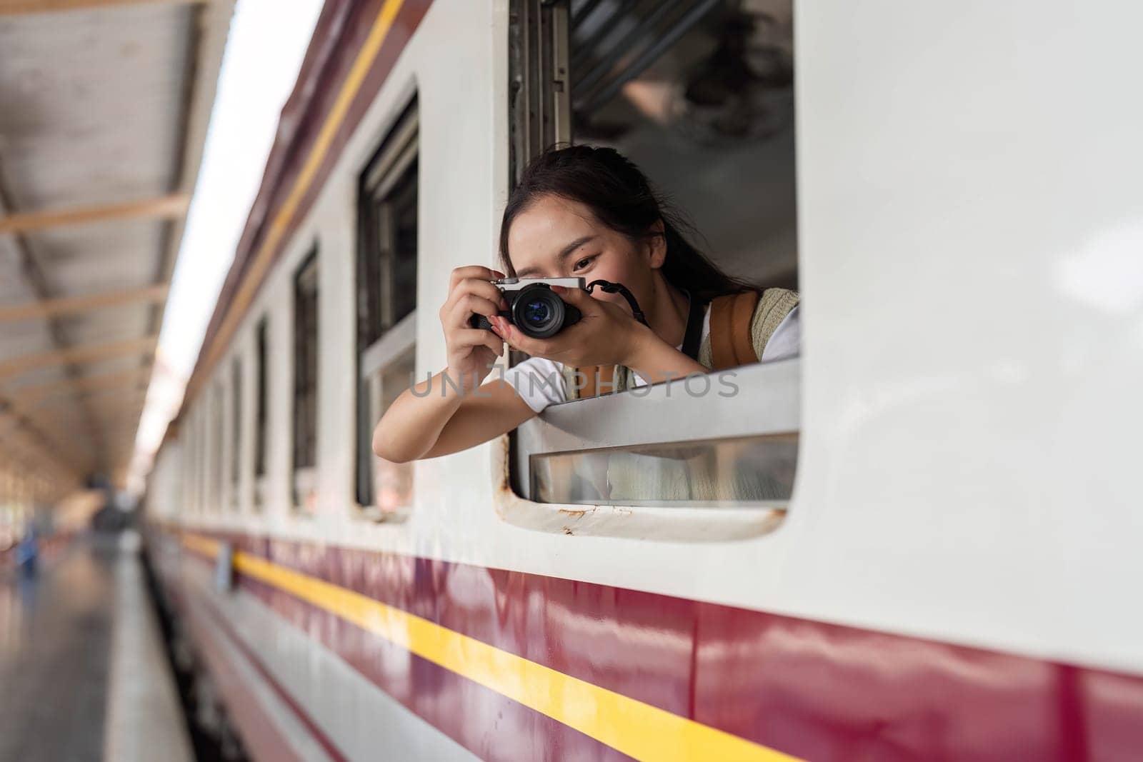 A traveler smiling as she prepares to photograph the scenery outside the train window, ready to document her adventures and experiences.