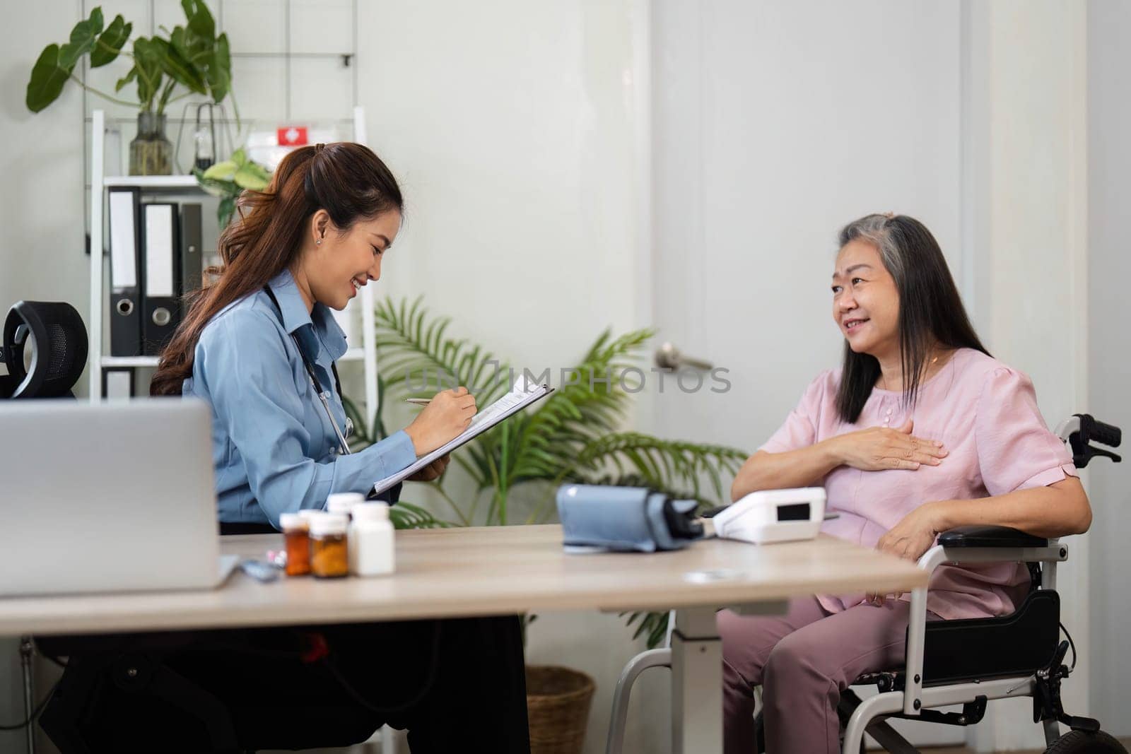 In a tranquil clinic, a nurse takes notes on health updates while engaging with a senior woman, ensuring her comfort and well-being during the medical checkup.