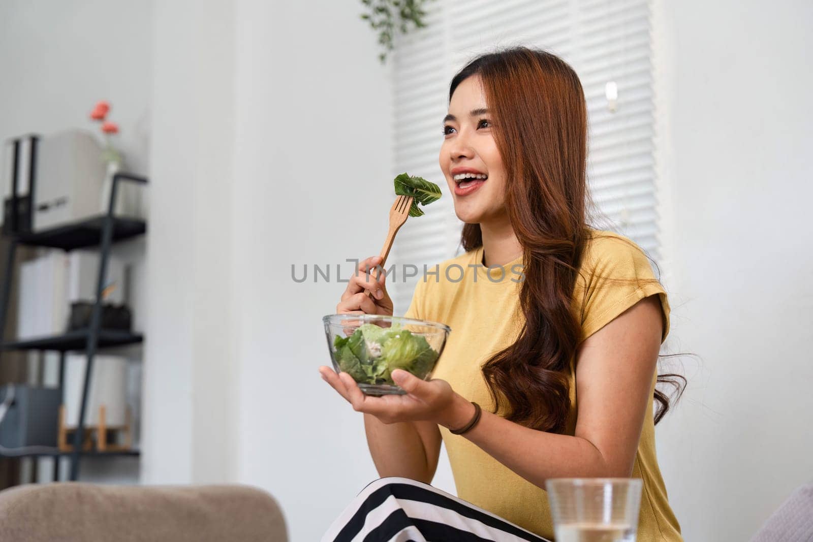 Enjoying a colorful salad at home, this woman embraces her morning routine with joy and vitality, highlighting the importance of healthy eating.