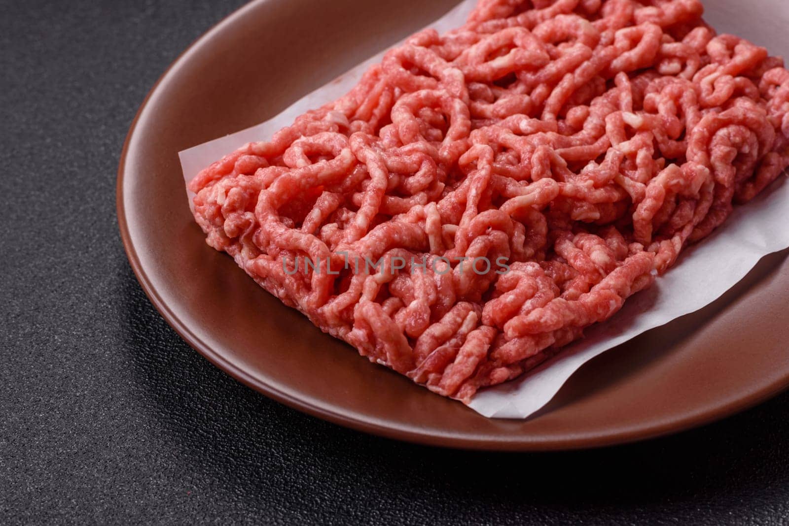 Stuffing or ground raw beef or pork with salt and spices on a black background