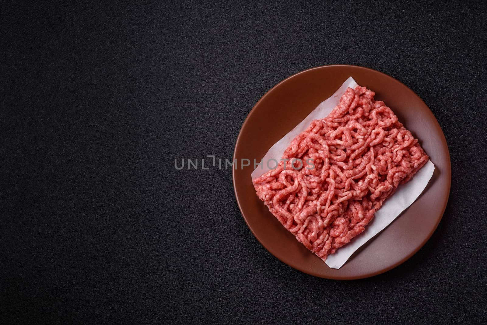Stuffing or ground raw beef or pork with salt and spices on a black background