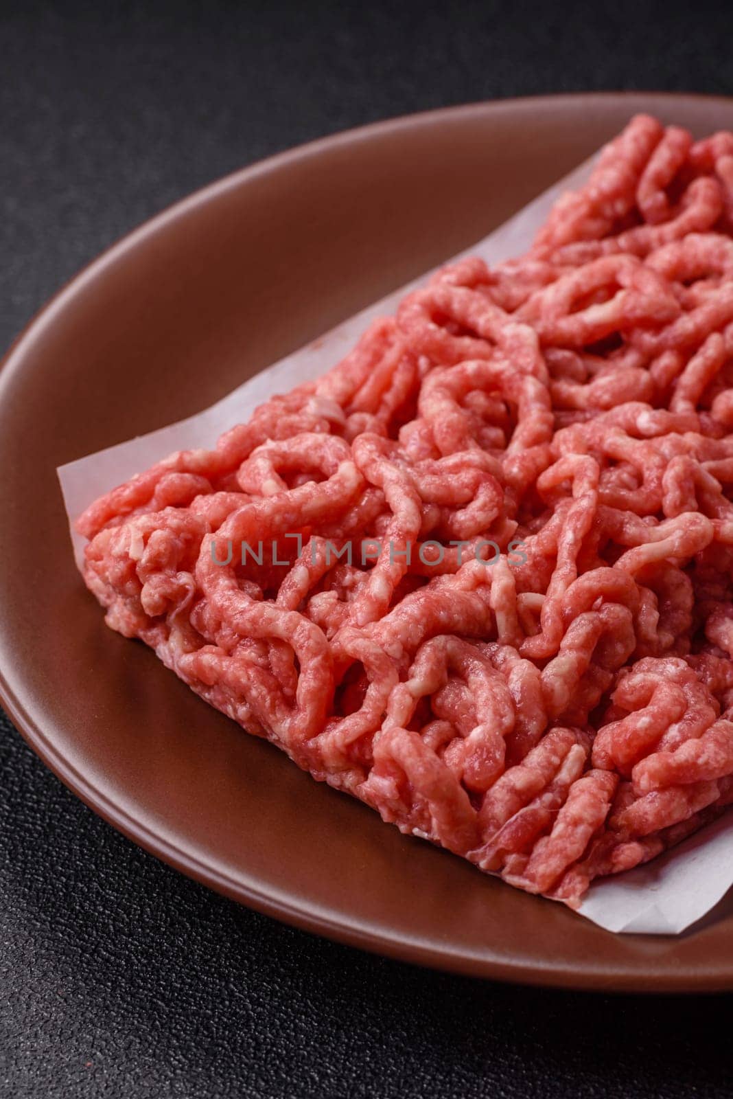 Stuffing or ground raw beef or pork with salt and spices on a black background